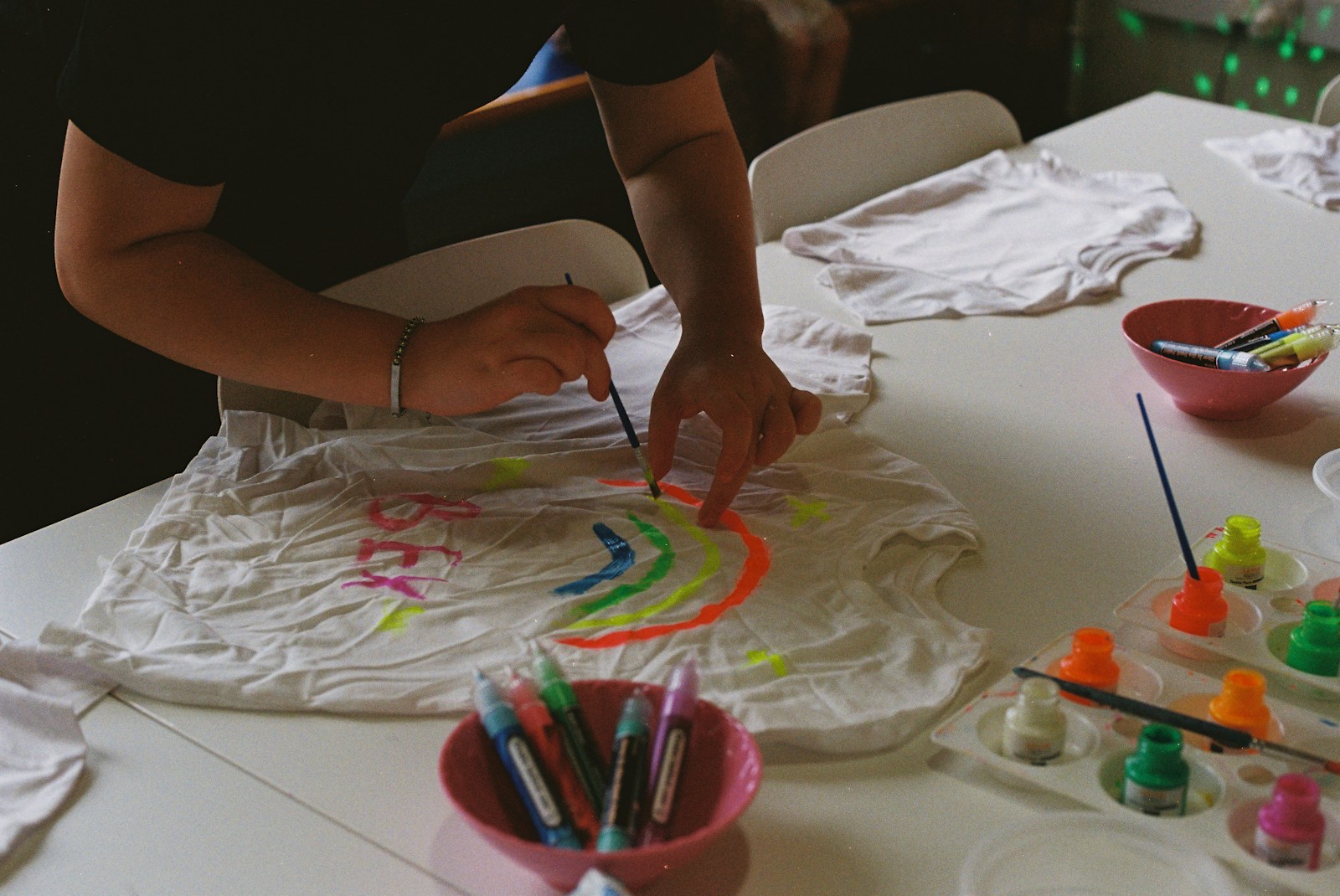 Painting a rainbow design on a white t-shirt with fabric paints