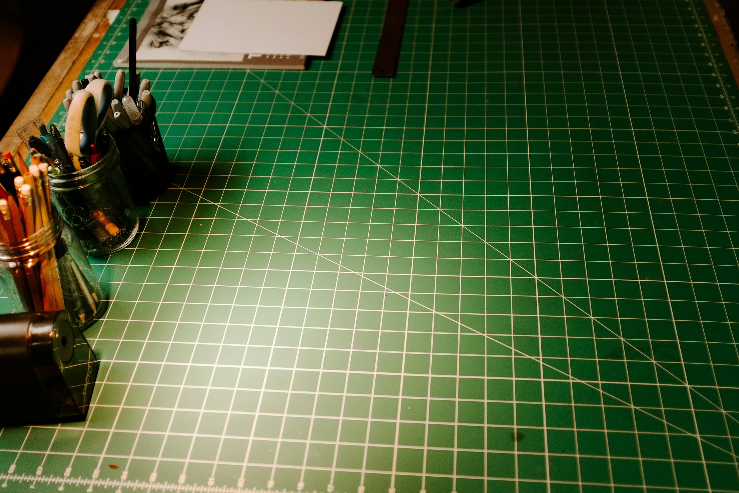 Green cutting mat with a craft knife and scissors for paper model making
