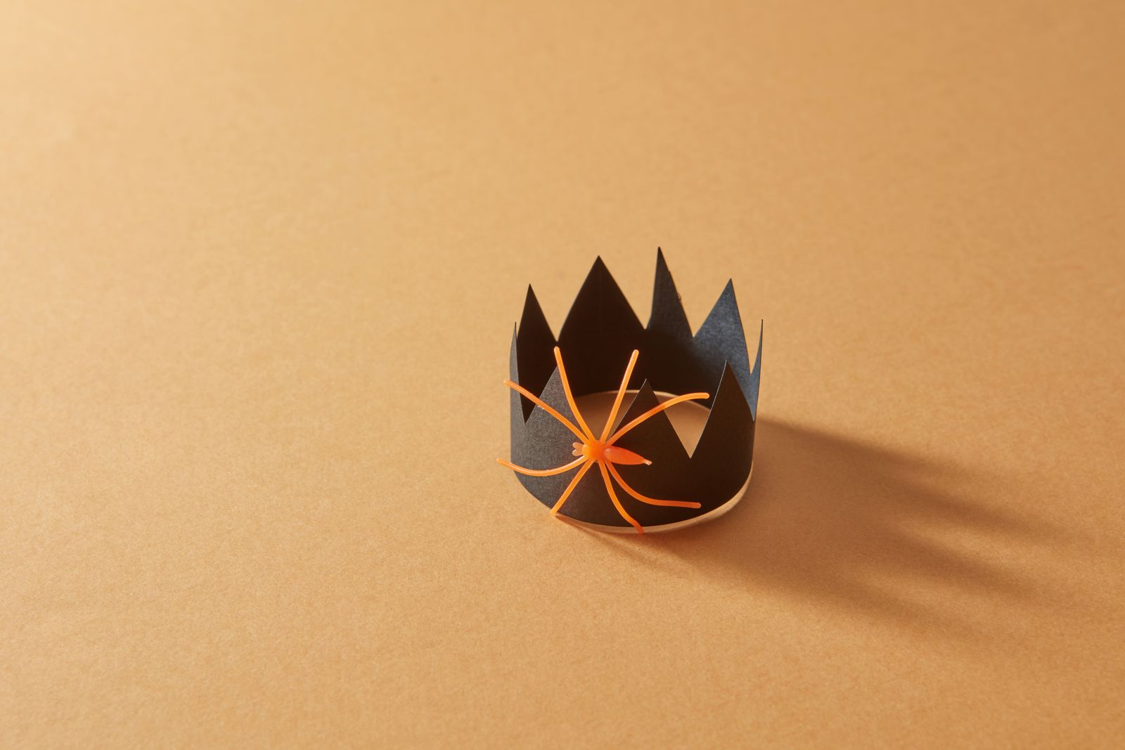 Black paper crown with a little orange spider on an orange background