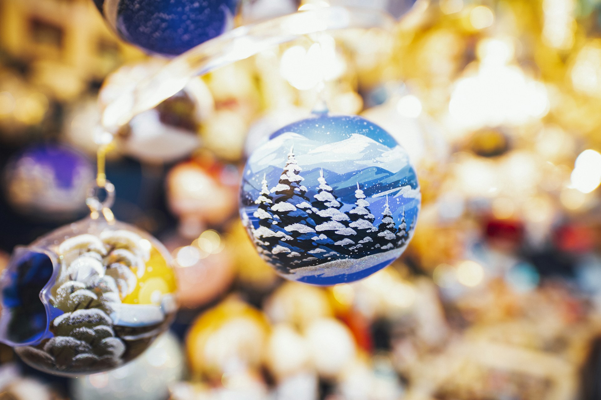 Hand painted ornaments with a snowy pine forest on a blue bauble