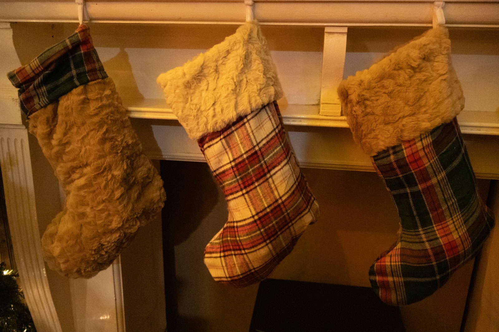 Plaid flannel Christmas stockings hanging on a wooden mantel