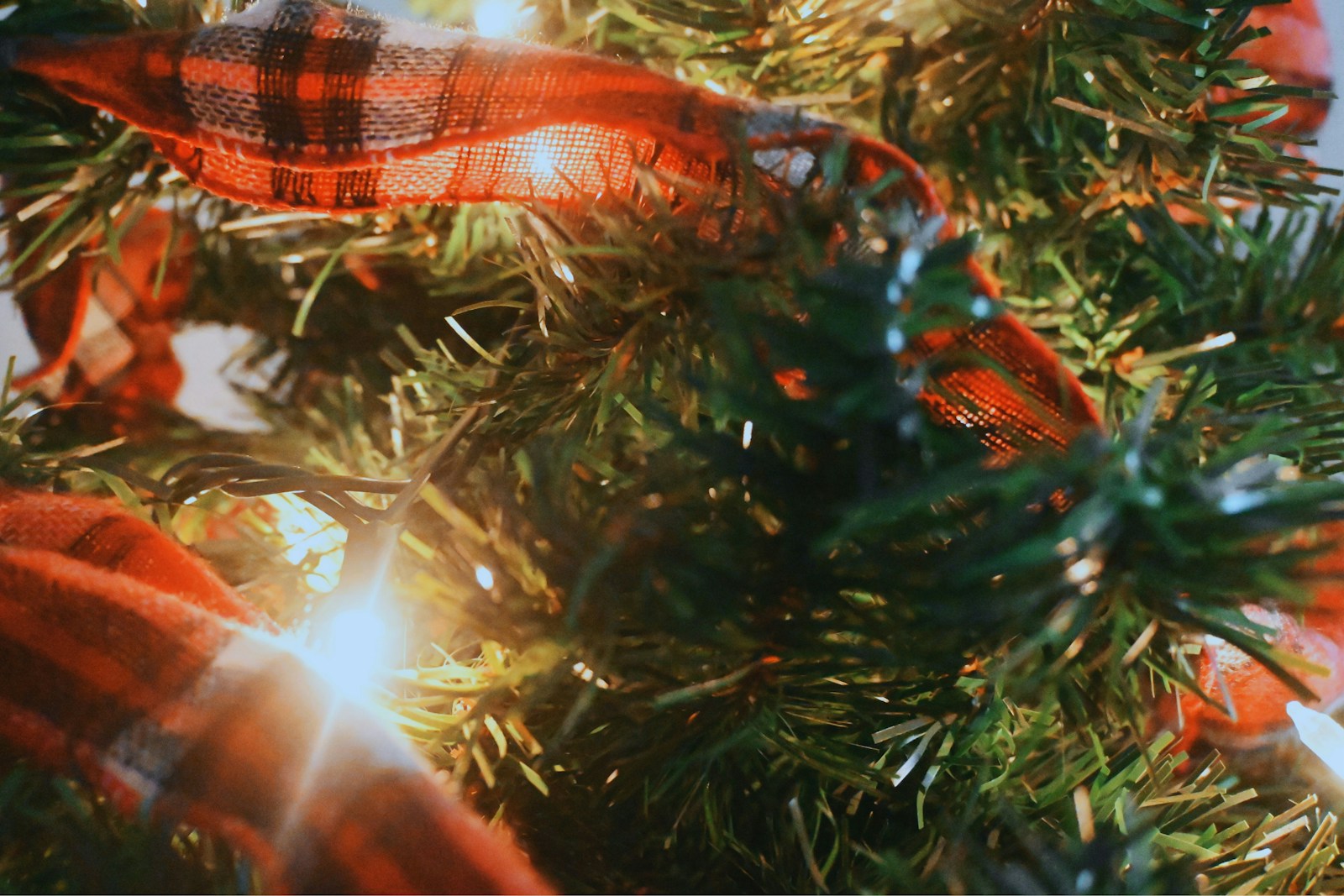 Plaid ribbon bow on a lit Christmas tree