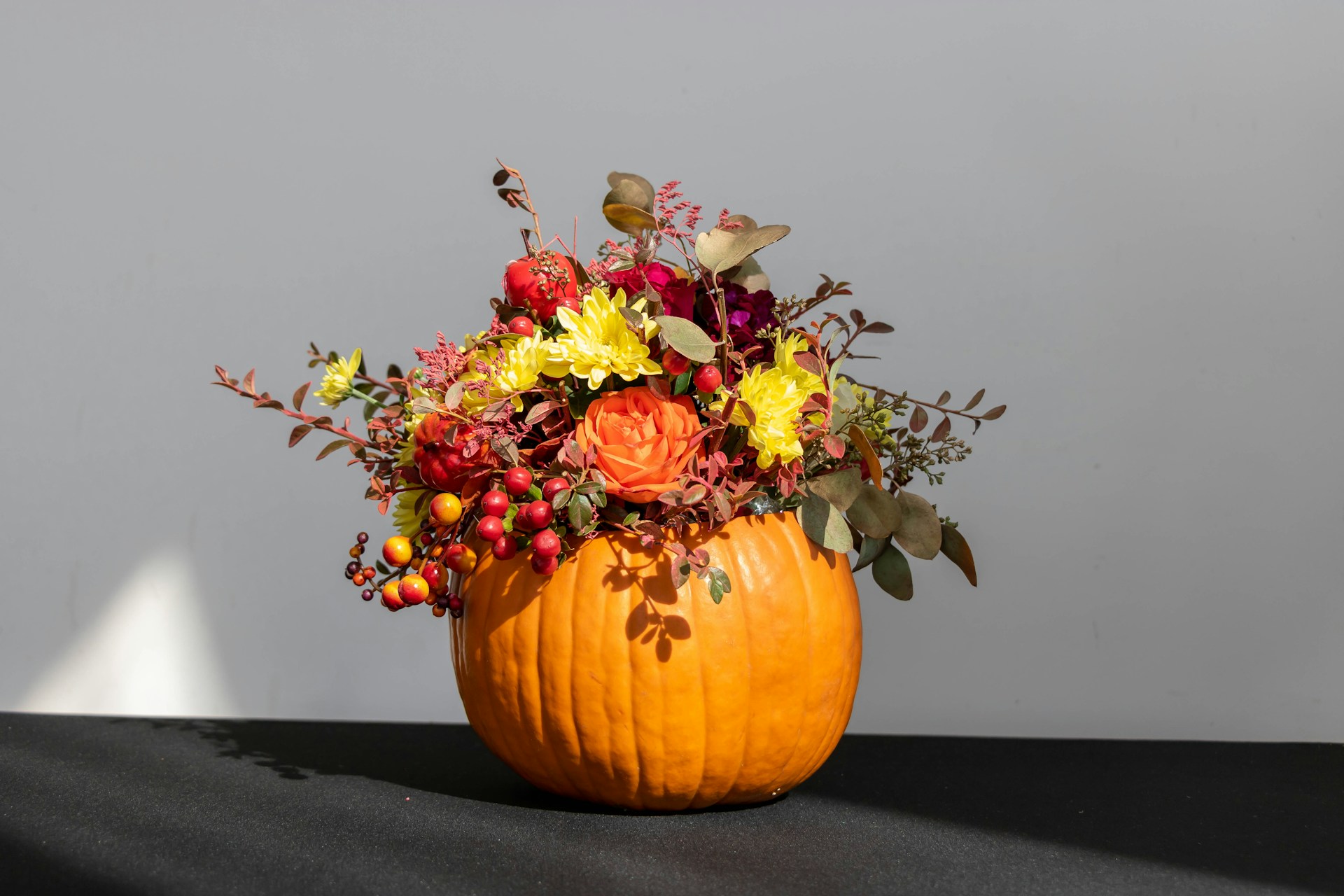 Pumpkin filled with fall flowers on a table