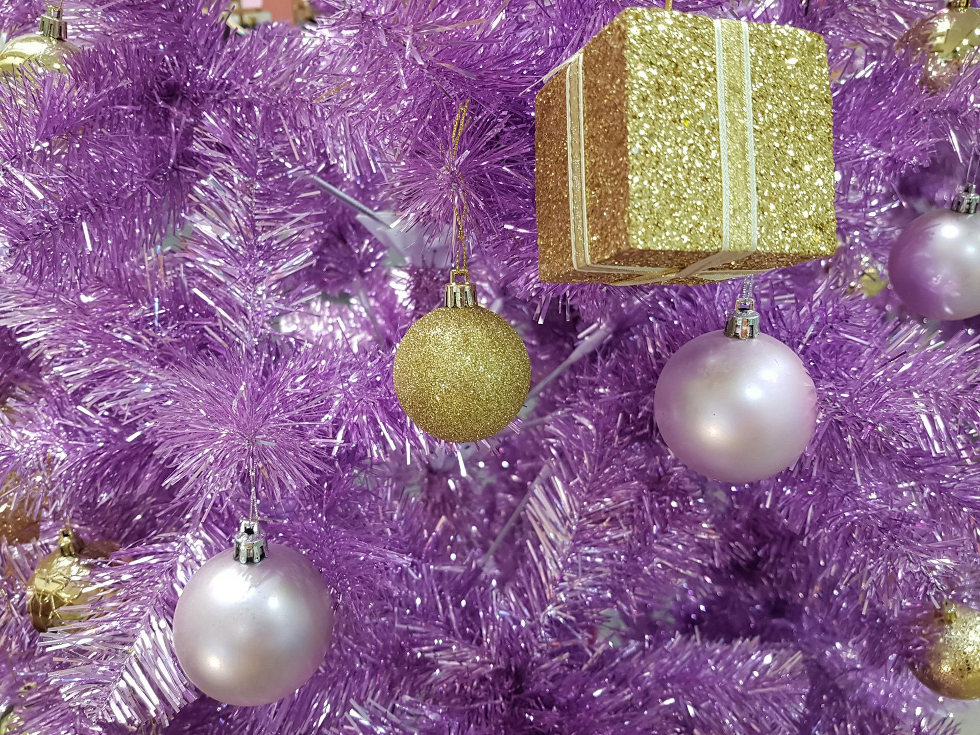 Gold and silver baubles on a purple Christmas tree