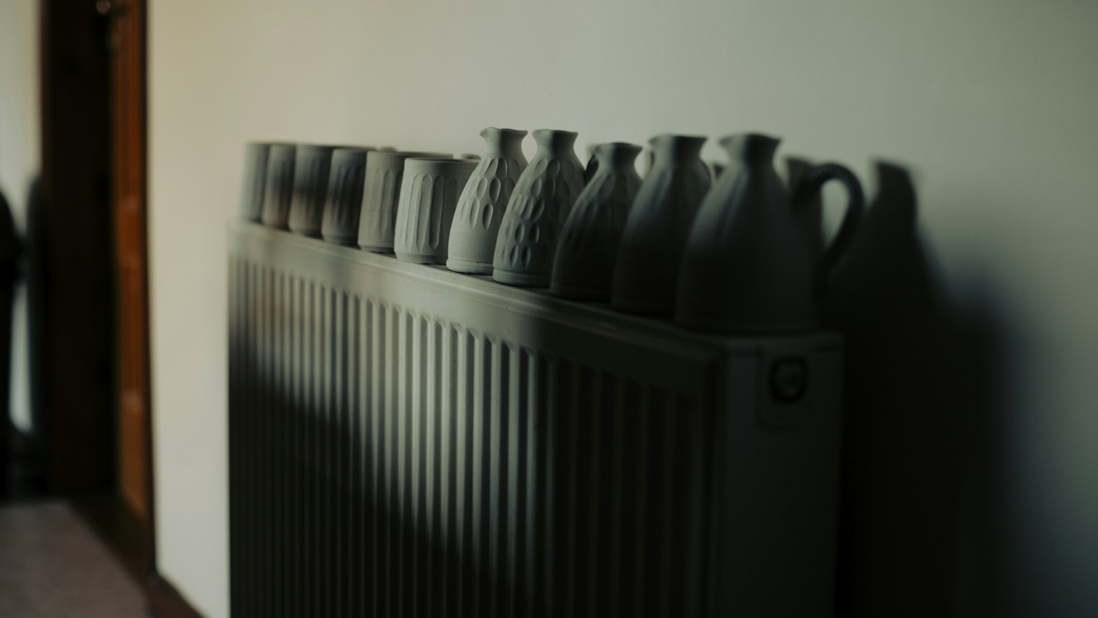 Row of ceramic vases lined up on top of a white radiator