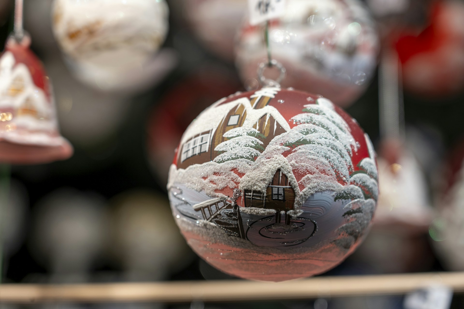 Glass ball with a snowy cabin under a red winter sky