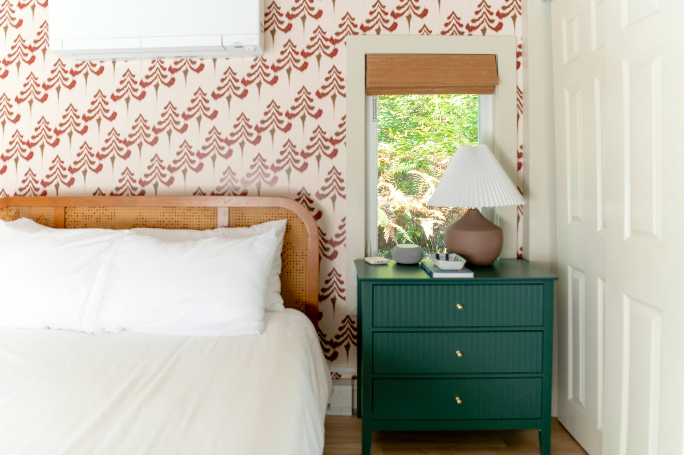 Bedroom with a cane headboard against a patterned wallpaper wall
