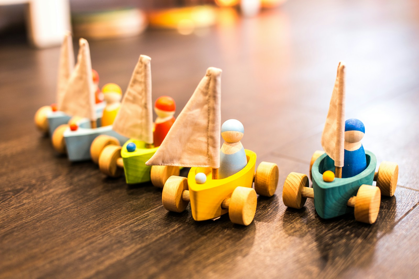 Row of small handmade wooden toy cars with little wooden drivers