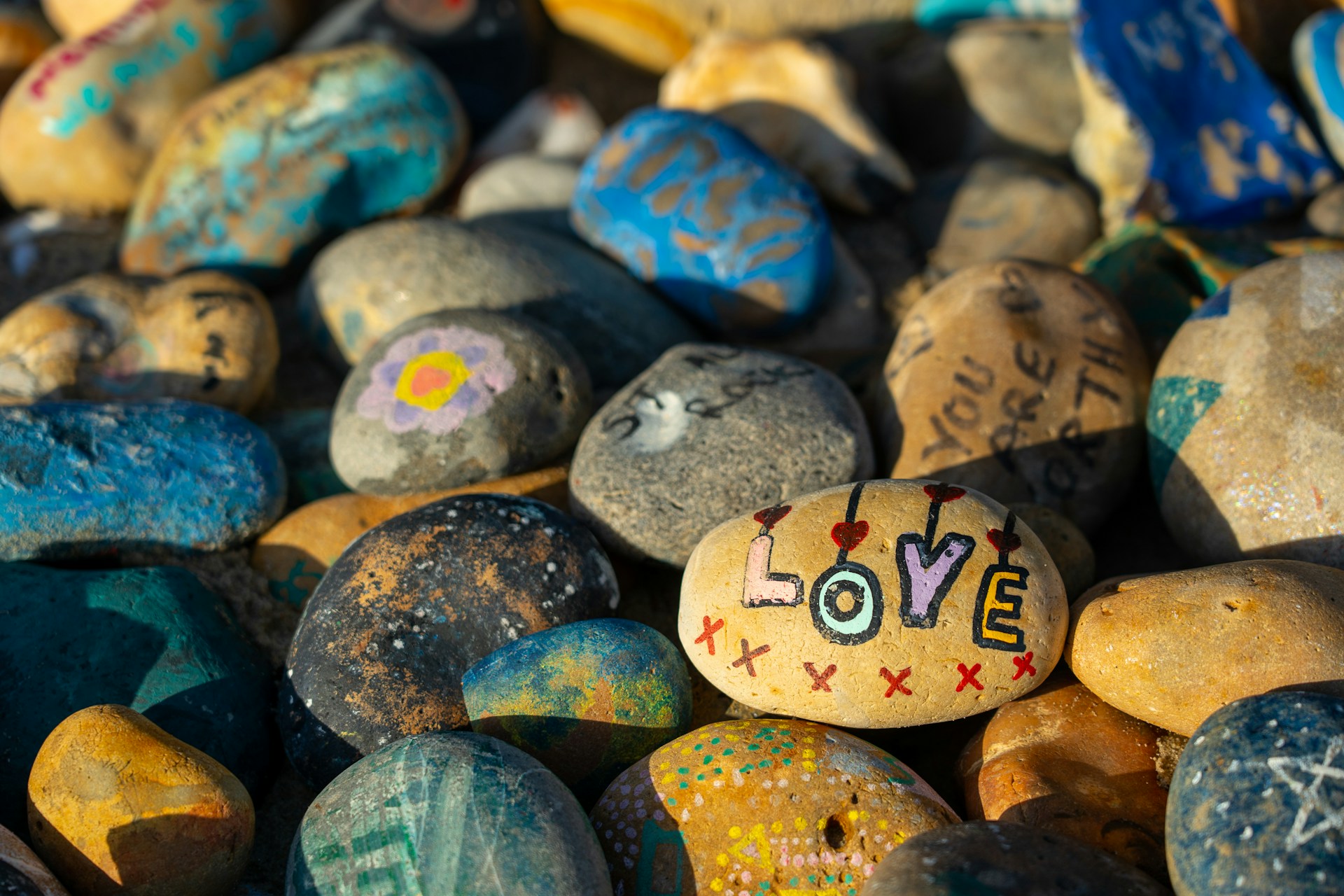 Pile of painted rocks with a stone painted with the word love