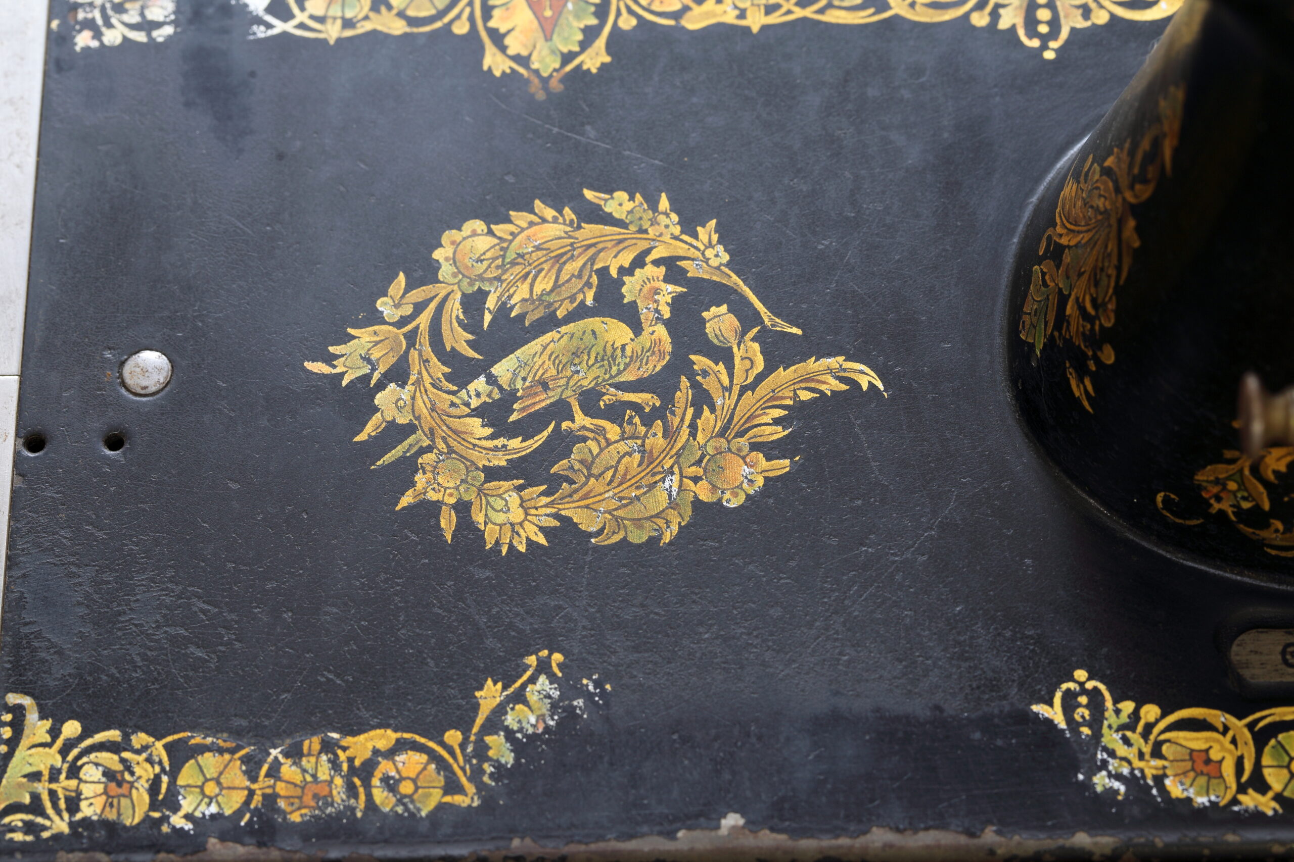 Glossy black antique sewing machine bed with a gold leaf decal