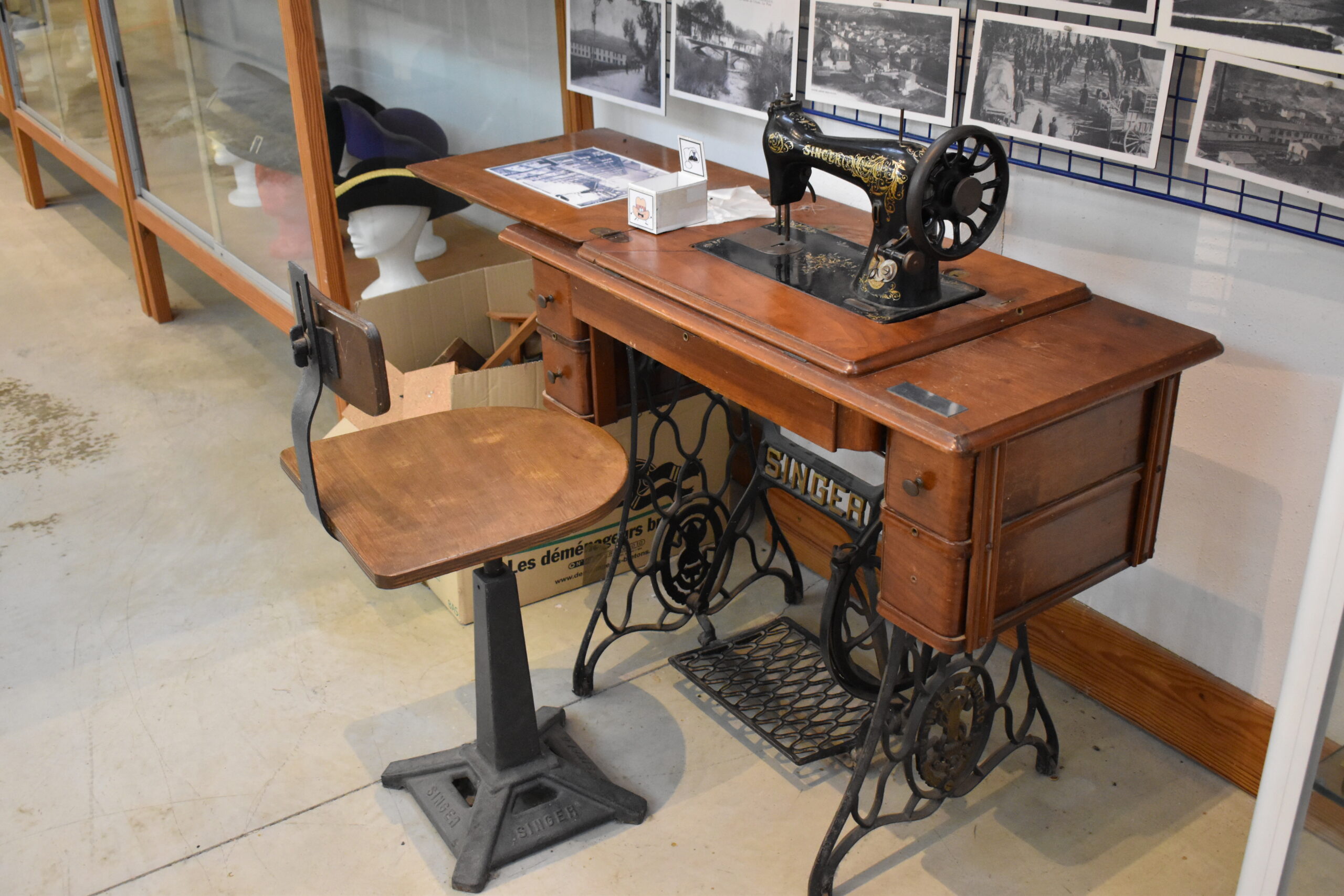 Antique treadle sewing machine on display with a wooden chair in a museum