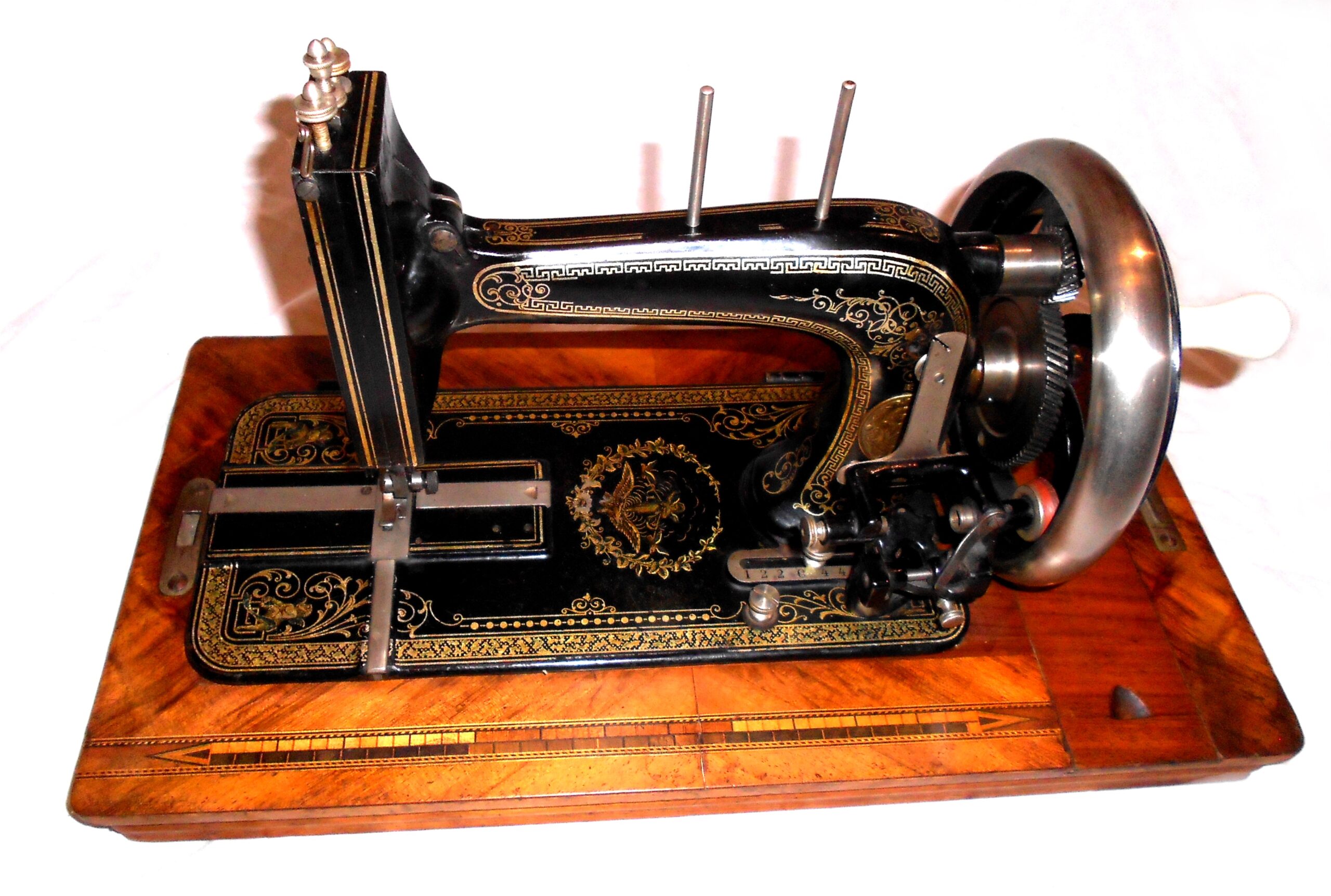 Antique hand crank sewing machine with shiny nickel faceplate and wheel on a wooden base