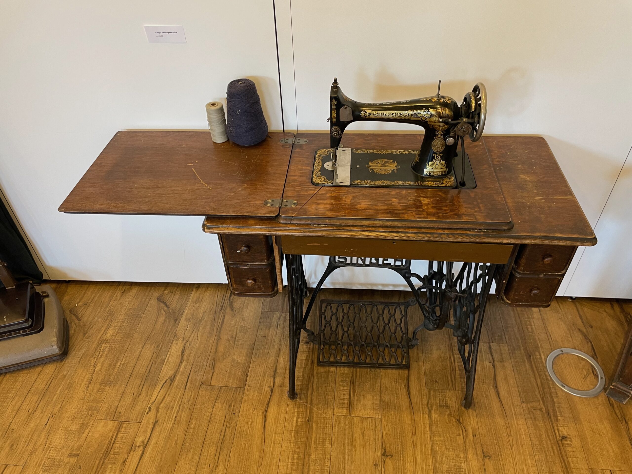 Antique sewing machine on a wooden treadle table with an iron foot pedal base