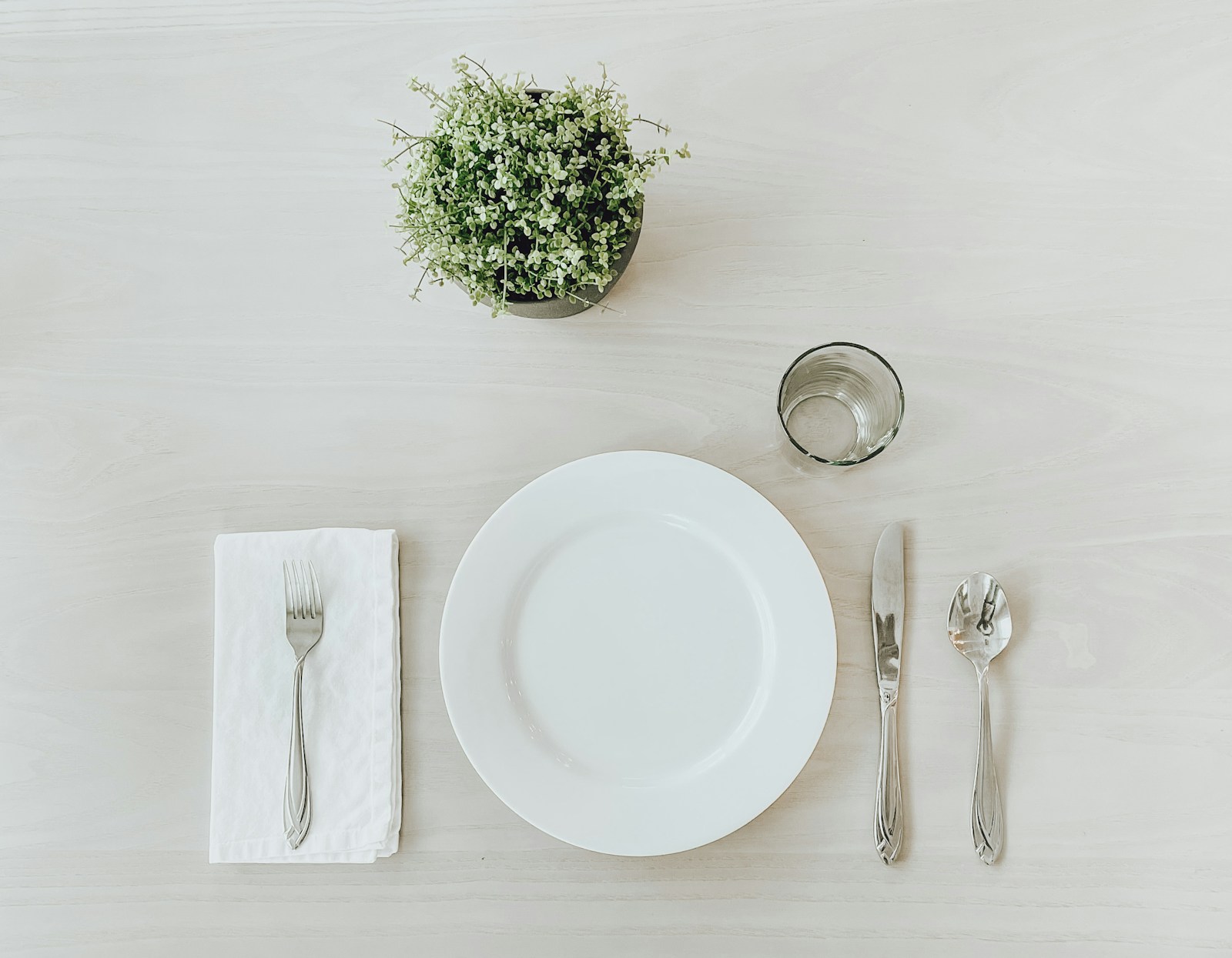 Emily Post Christmas table basics: plate, fork and bread knife on white linen
