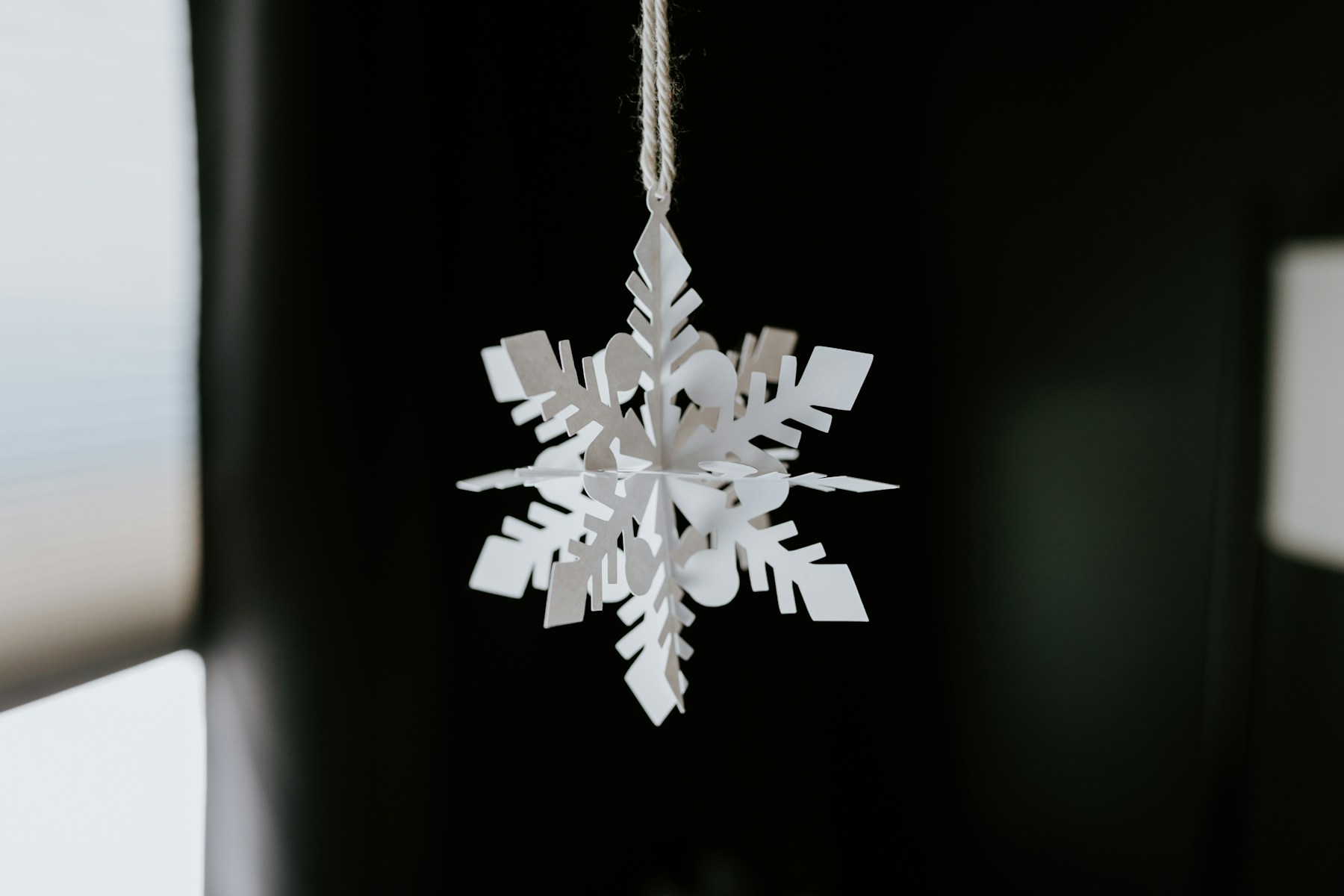 White snowflake decoration hanging in a window, recycled Christmas decorations for winter