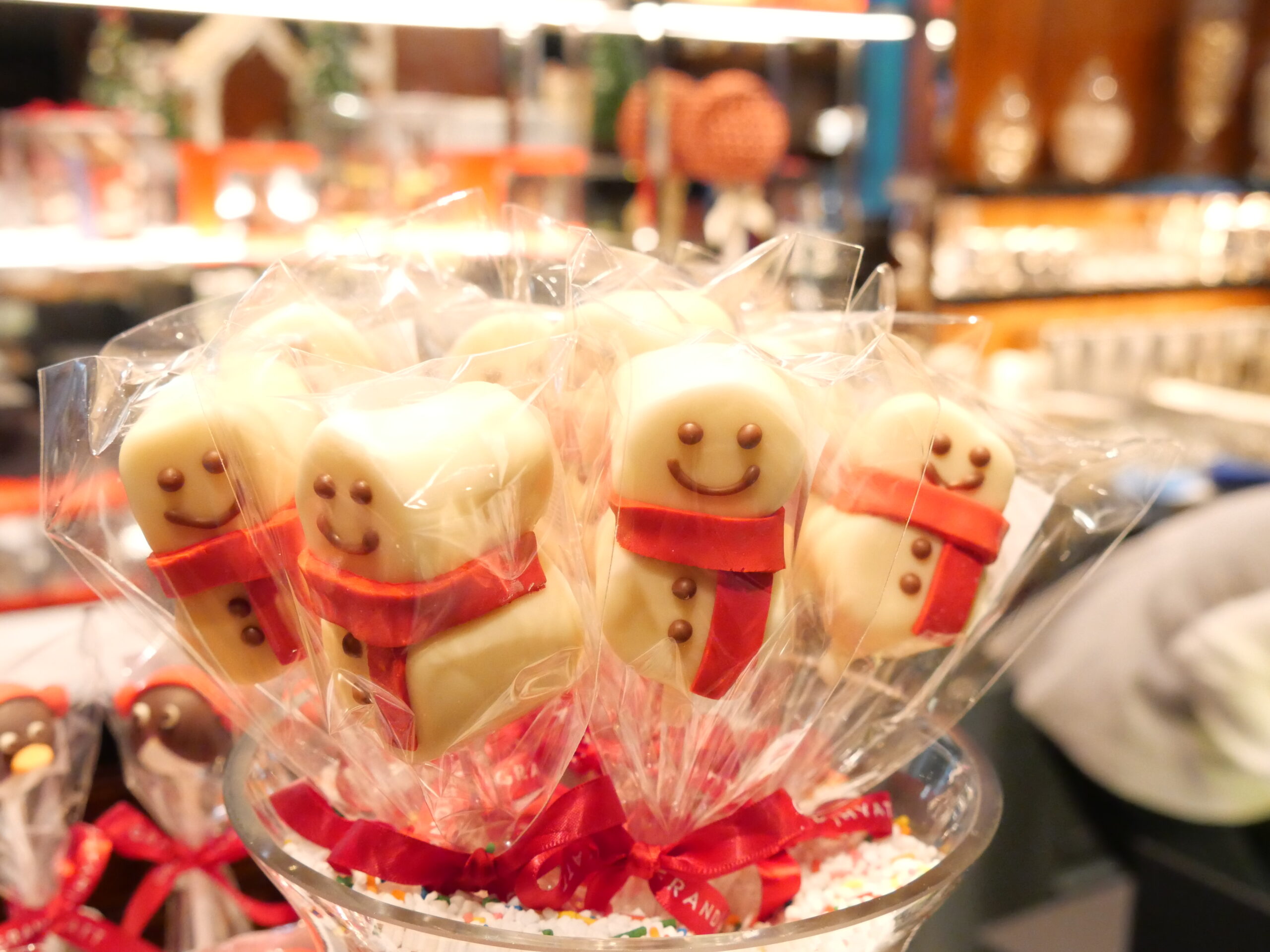 Wrapped marshmallow snowmen on sticks with red scarves in a bakery