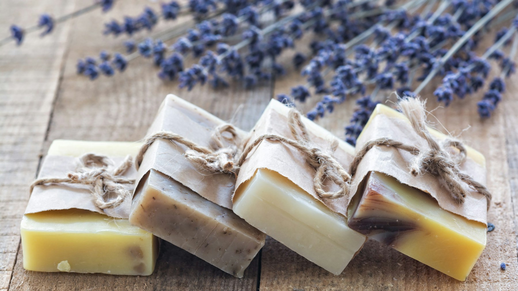 DIY Christmas soap bars wrapped in kraft paper bands and tied with twine beside lavender