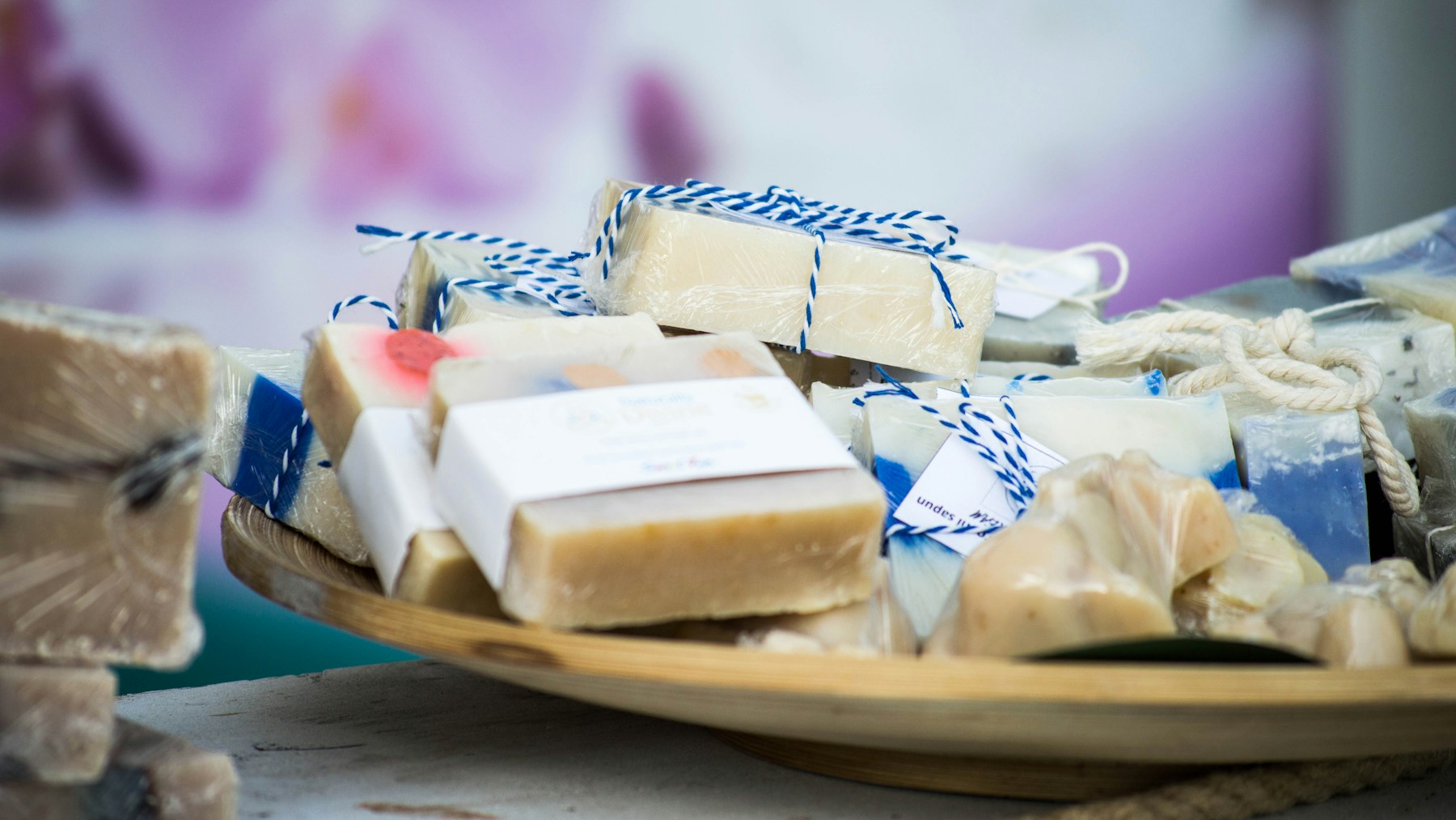 Small handmade soap bars wrapped in paper and twine as party favors in a wooden bowl