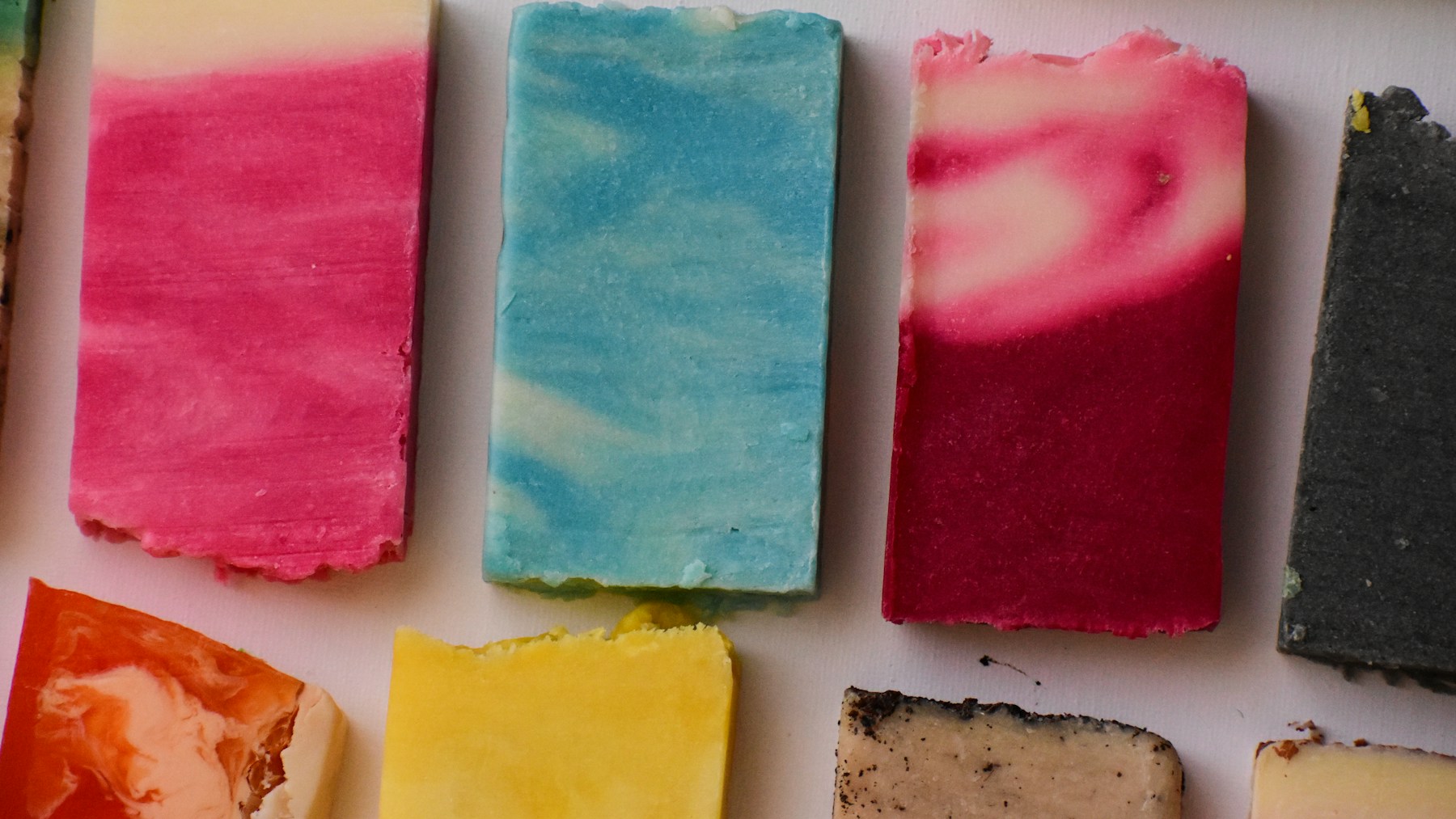 DIY Christmas soap bars in bright red, white, blue and yellow swirls laid out in a row