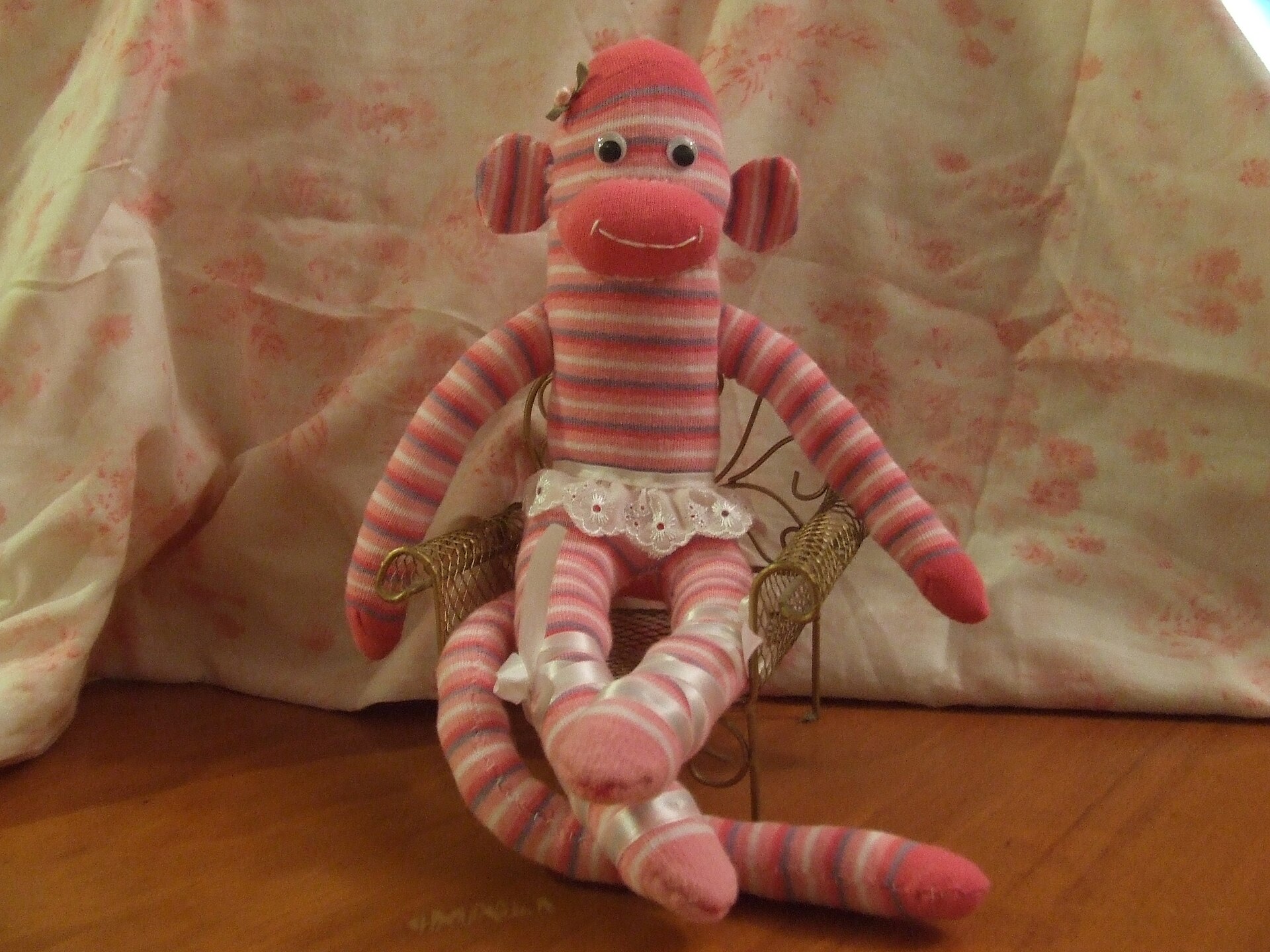 Pink striped sock monkey in a tutu sitting on a chair