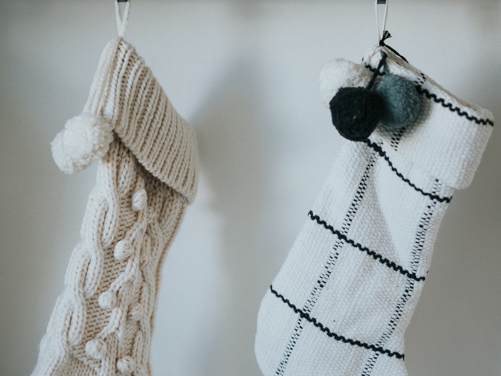 Cream cable knit and black check stockings hanging on wall hooks