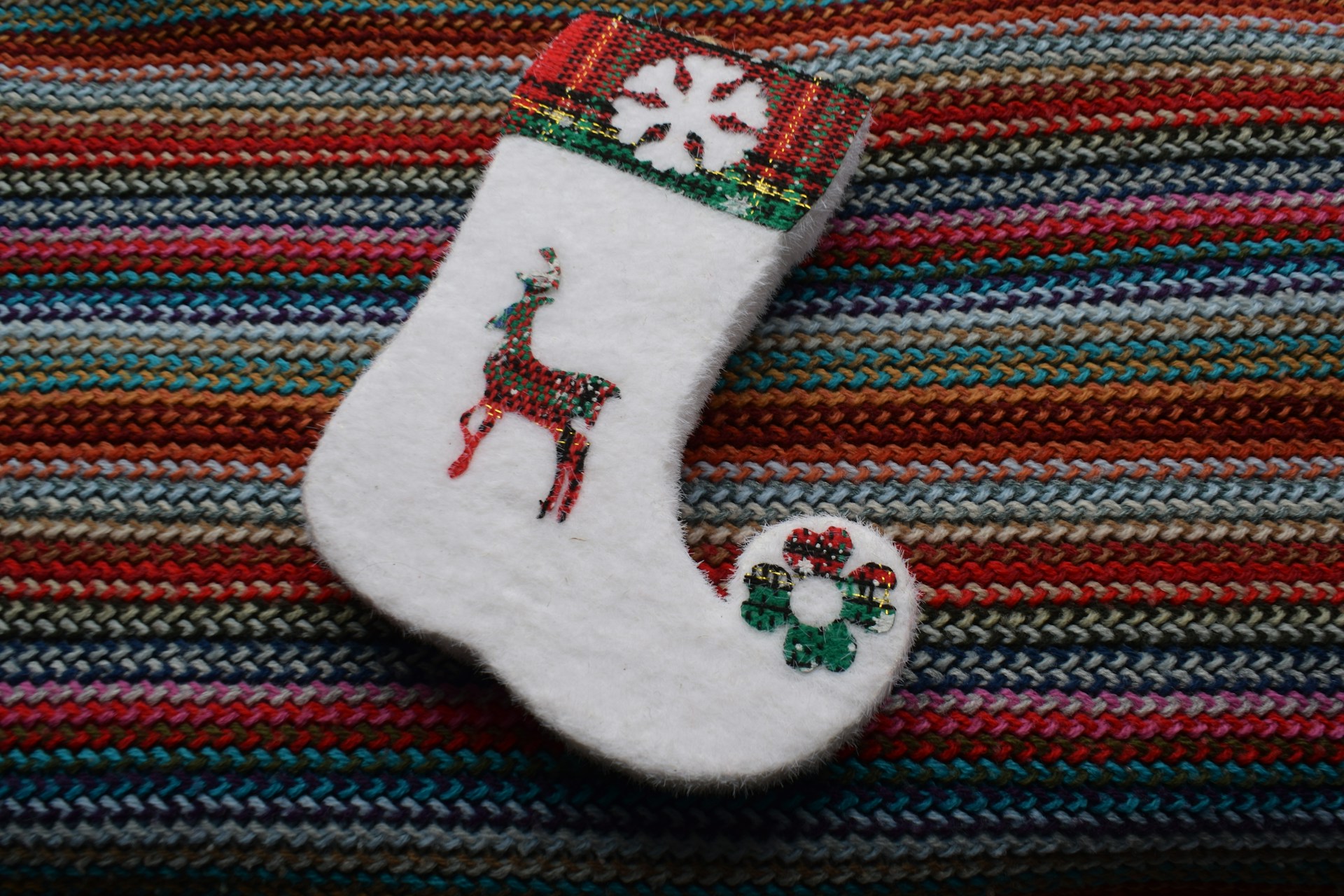 White Christmas stocking with a red reindeer design on a striped blanket