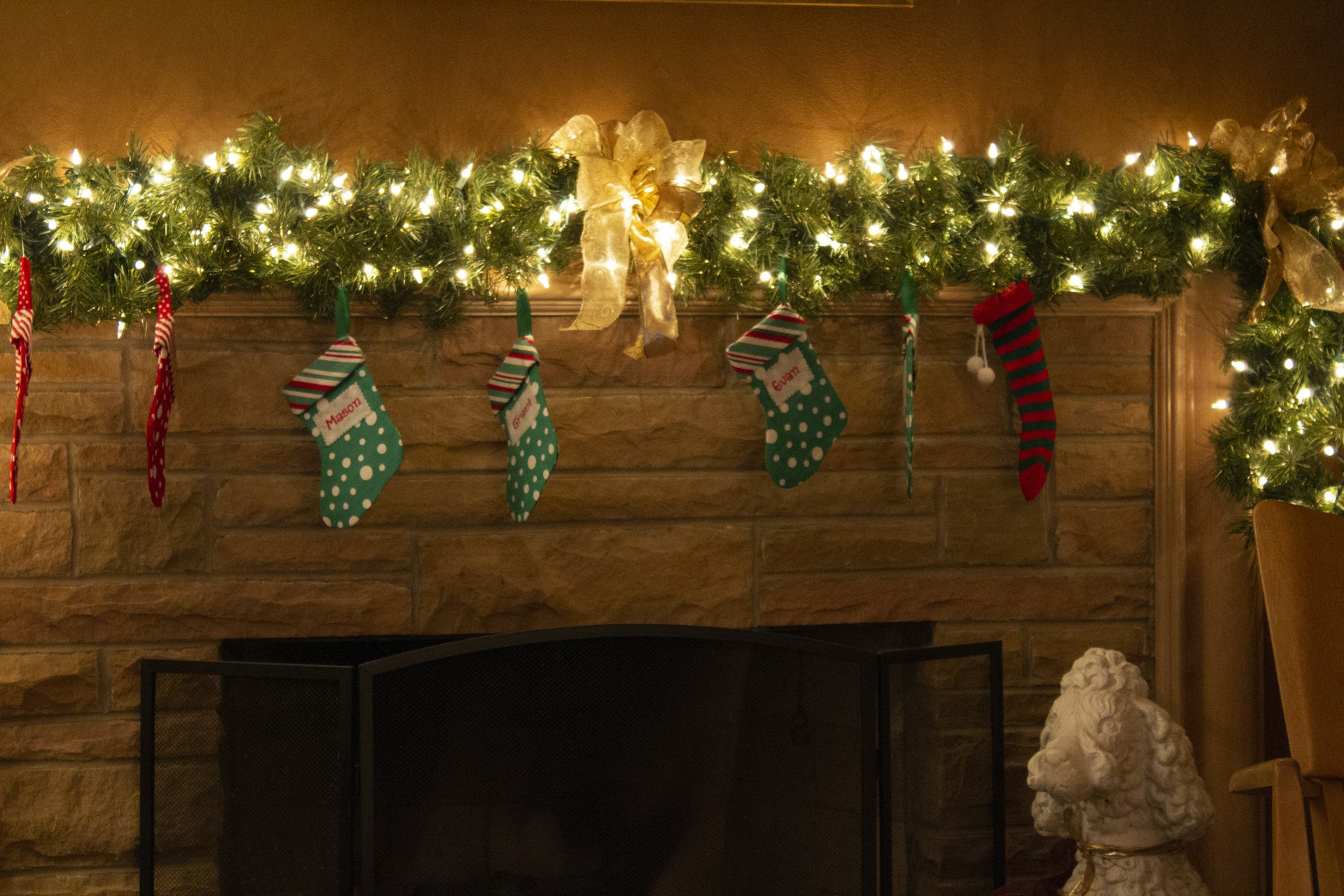 Mantel with a lit pine garland and DIY Christmas stockings hanging below