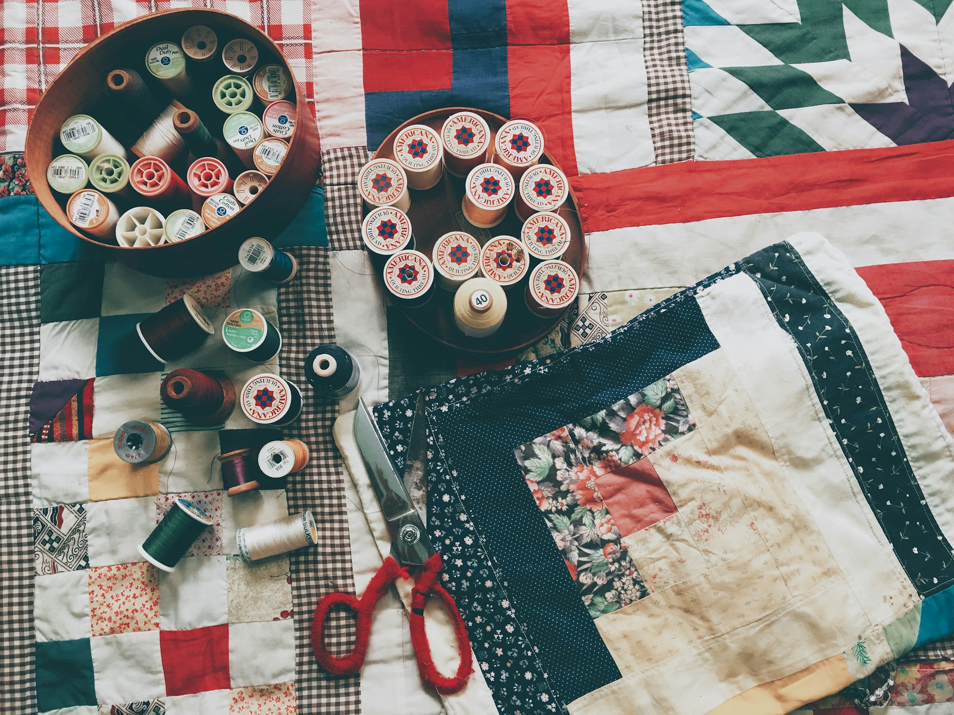 Holiday print quilt fabric squares with spools of thread and scissors