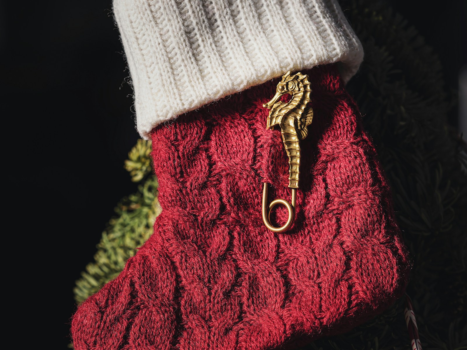 DIY Christmas stockings idea: a red cable knit stocking with a cream sweater cuff hanging on a tree