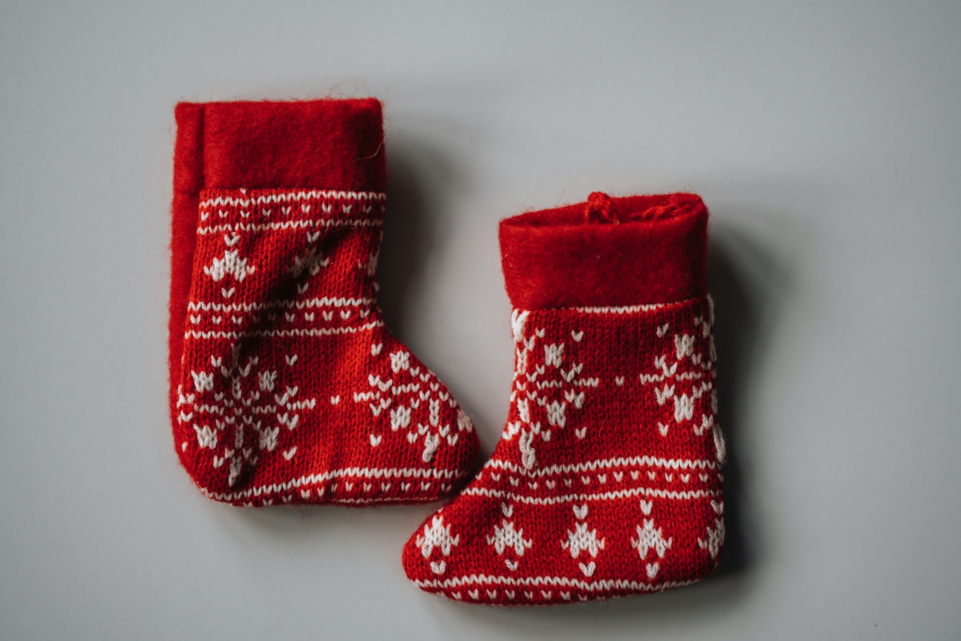 Two mini red knit DIY Christmas stockings with white Nordic patterns