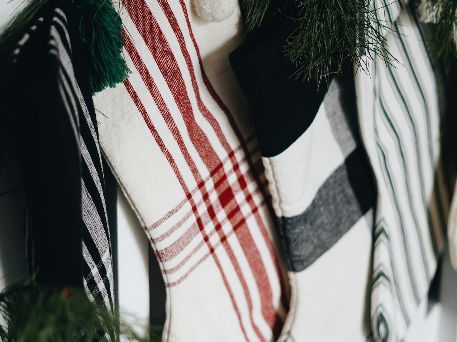 DIY Christmas stockings with grain sack style red stripes hanging near a pine tree
