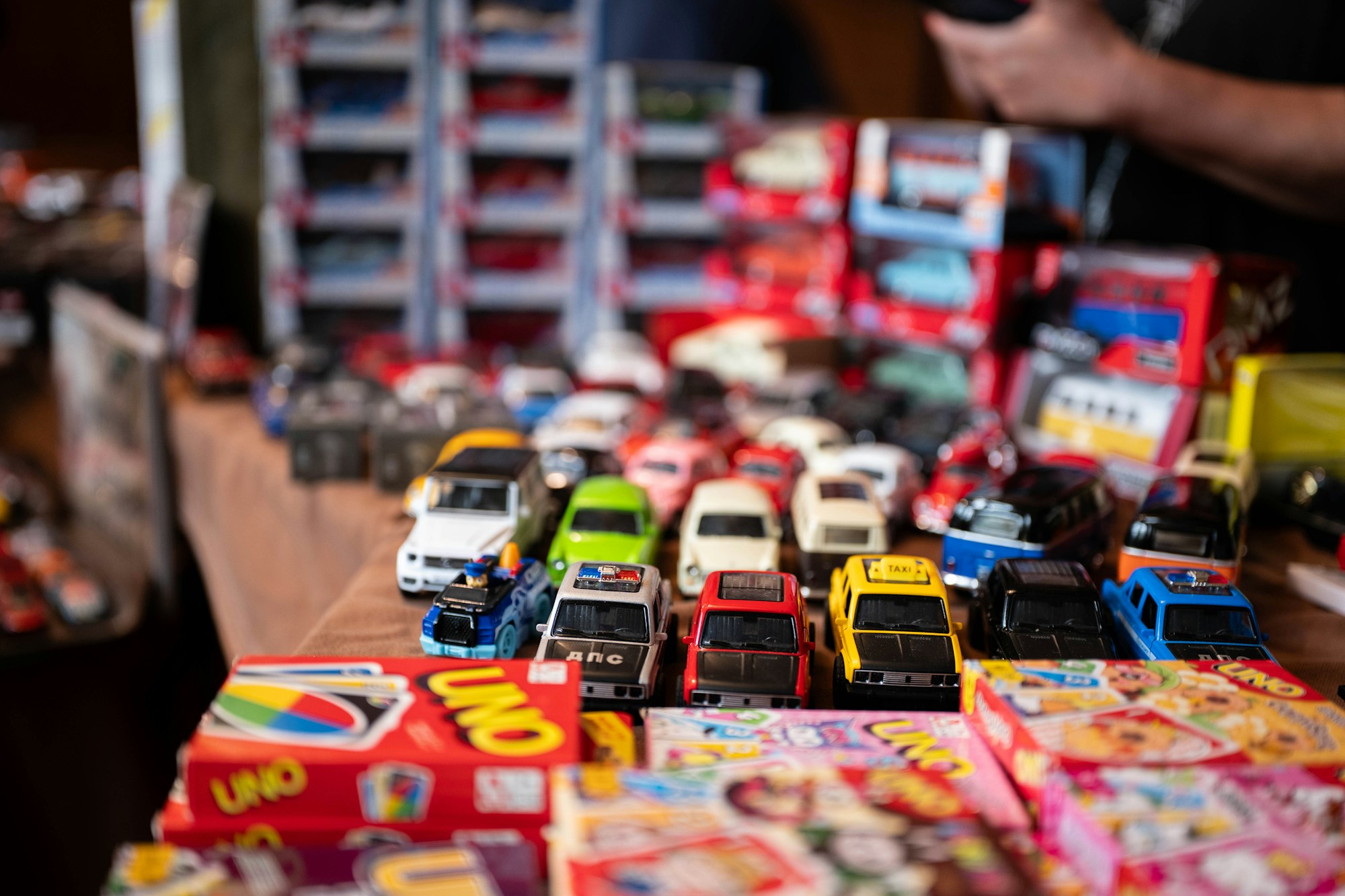 A table covered in colorful old toy cars and games, like a flea market find