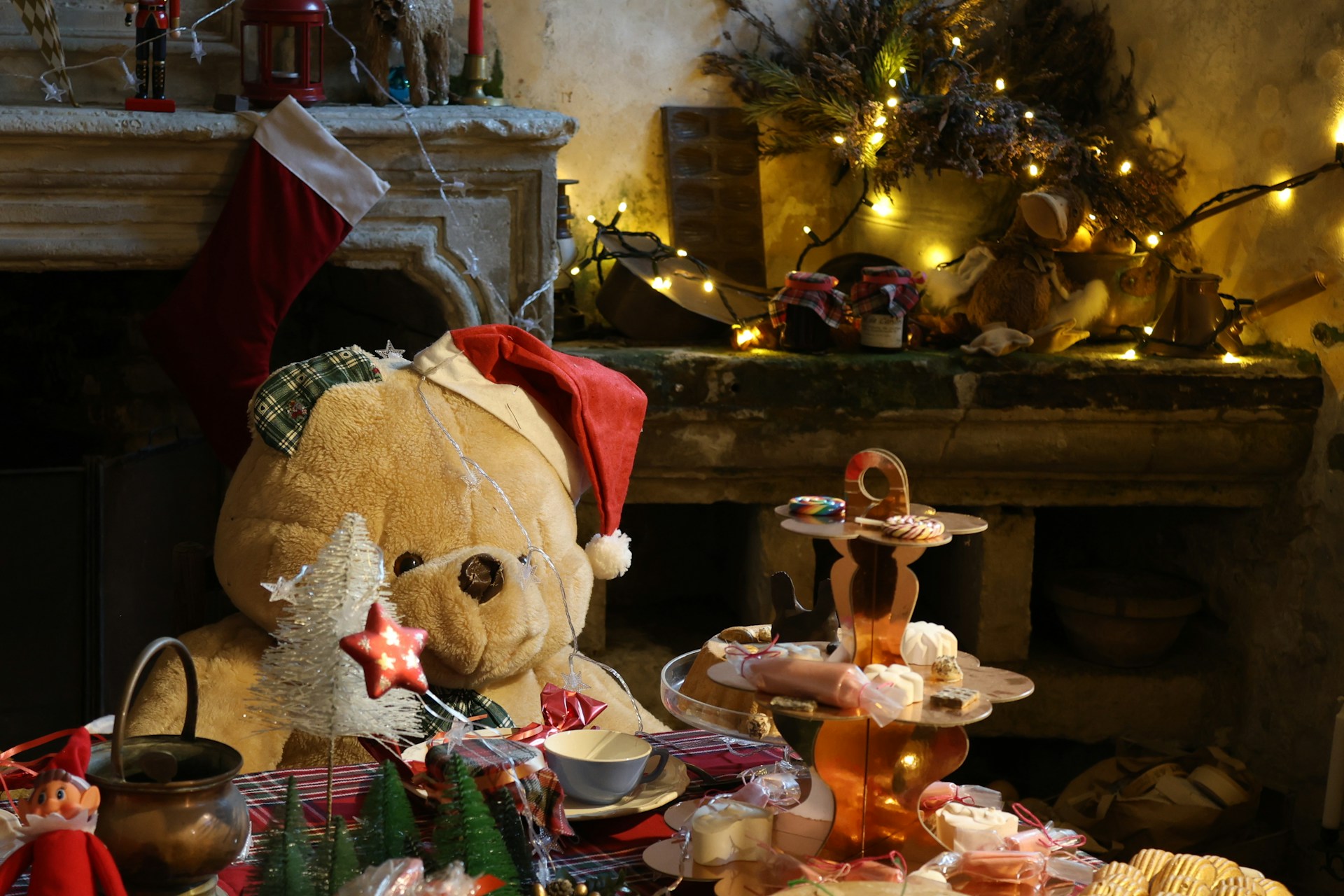 Teddy bear in a Santa hat by a mantel with stockings and a tray of treats
