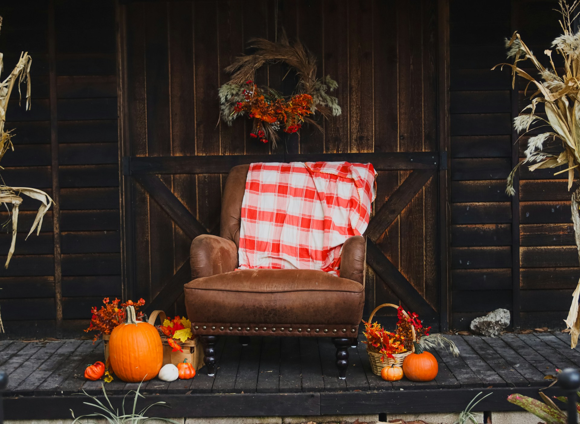 Leather armchair with a red plaid blanket on a porch with pumpkins