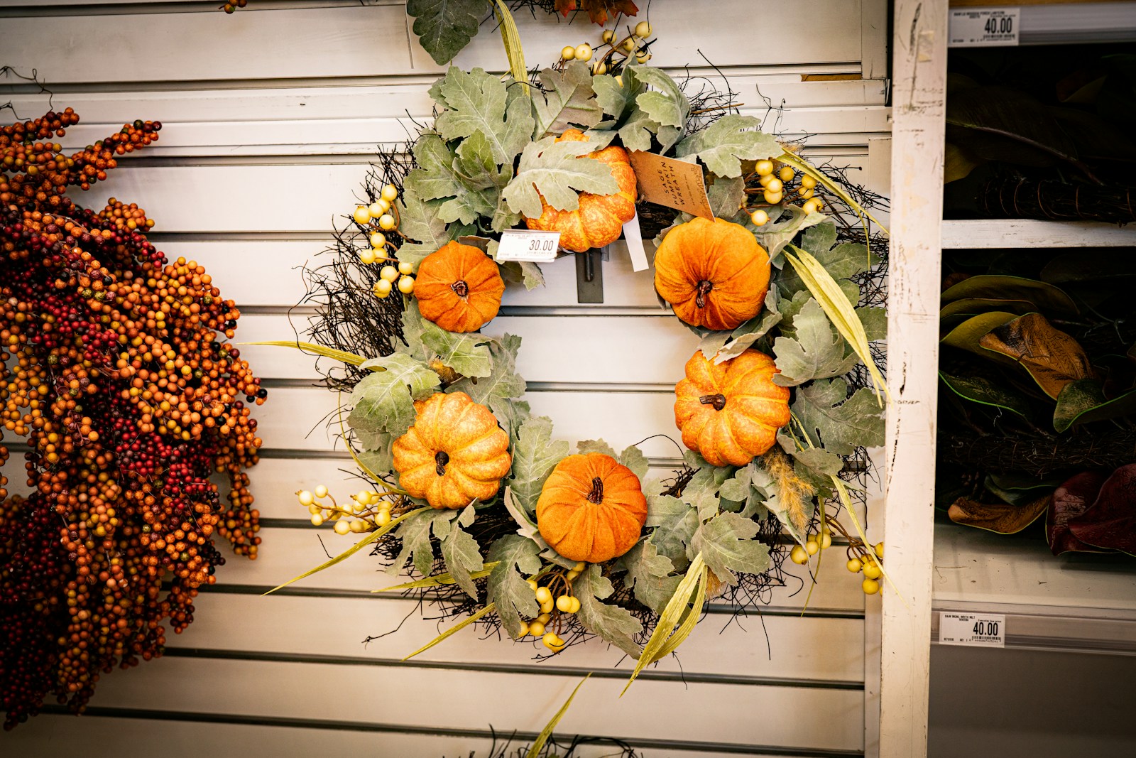 A wreath of mini pumpkins, gourds and dried greenery on a wall