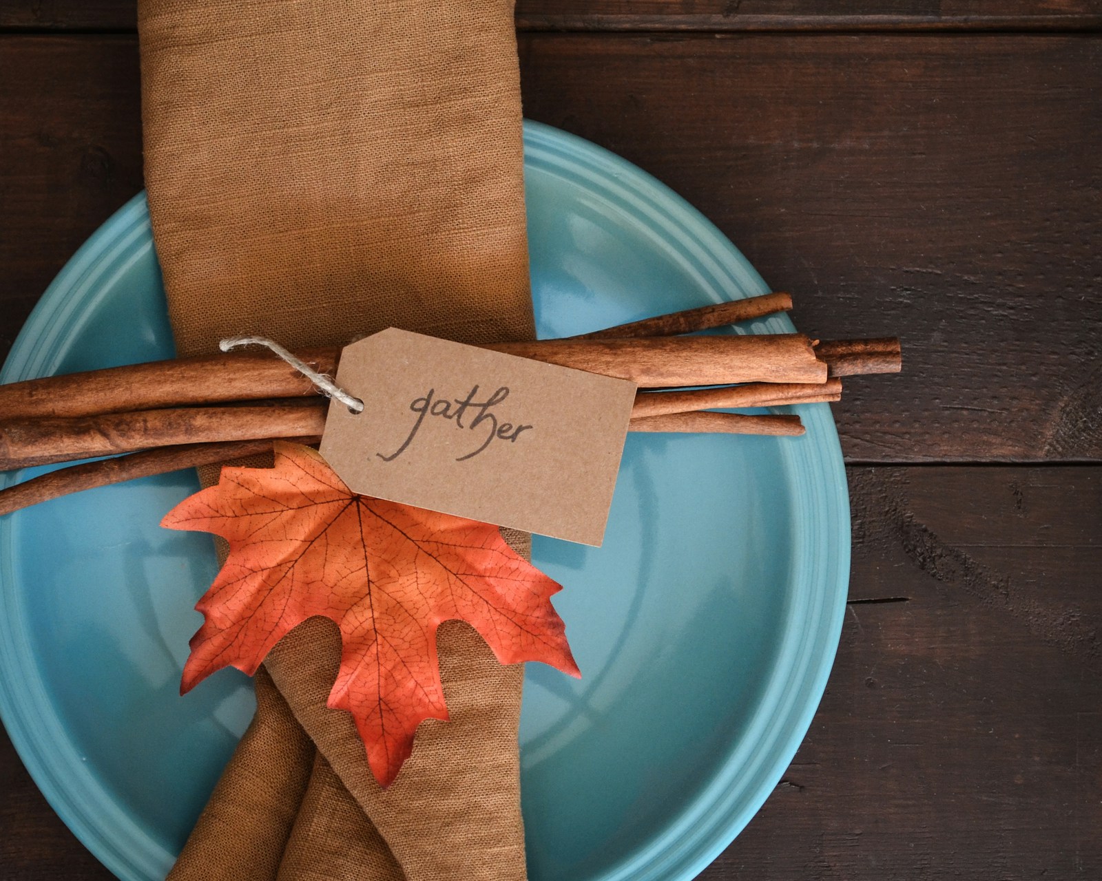 Blue plate with a tag place card, cinnamon sticks and an orange maple leaf