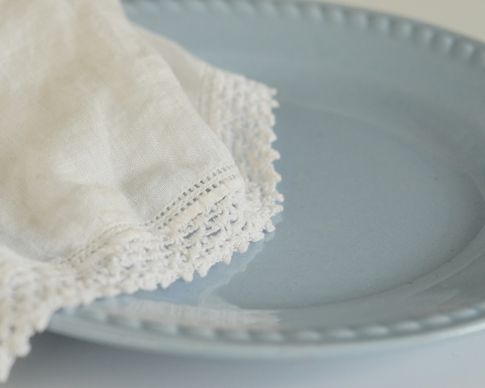 White lace edged linen napkin resting on a pale blue oval platter