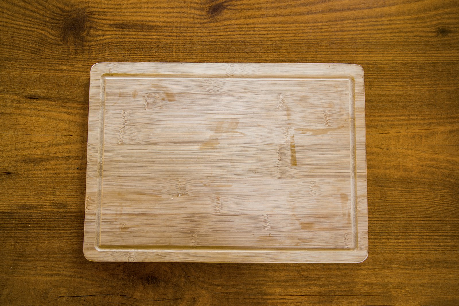 Smooth wooden cutting board with a groove edge on a warm wood table