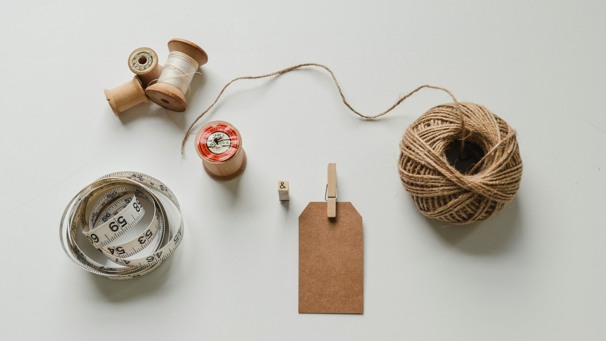 Spools of twine, thread and a kraft paper tag laid out for a craft project