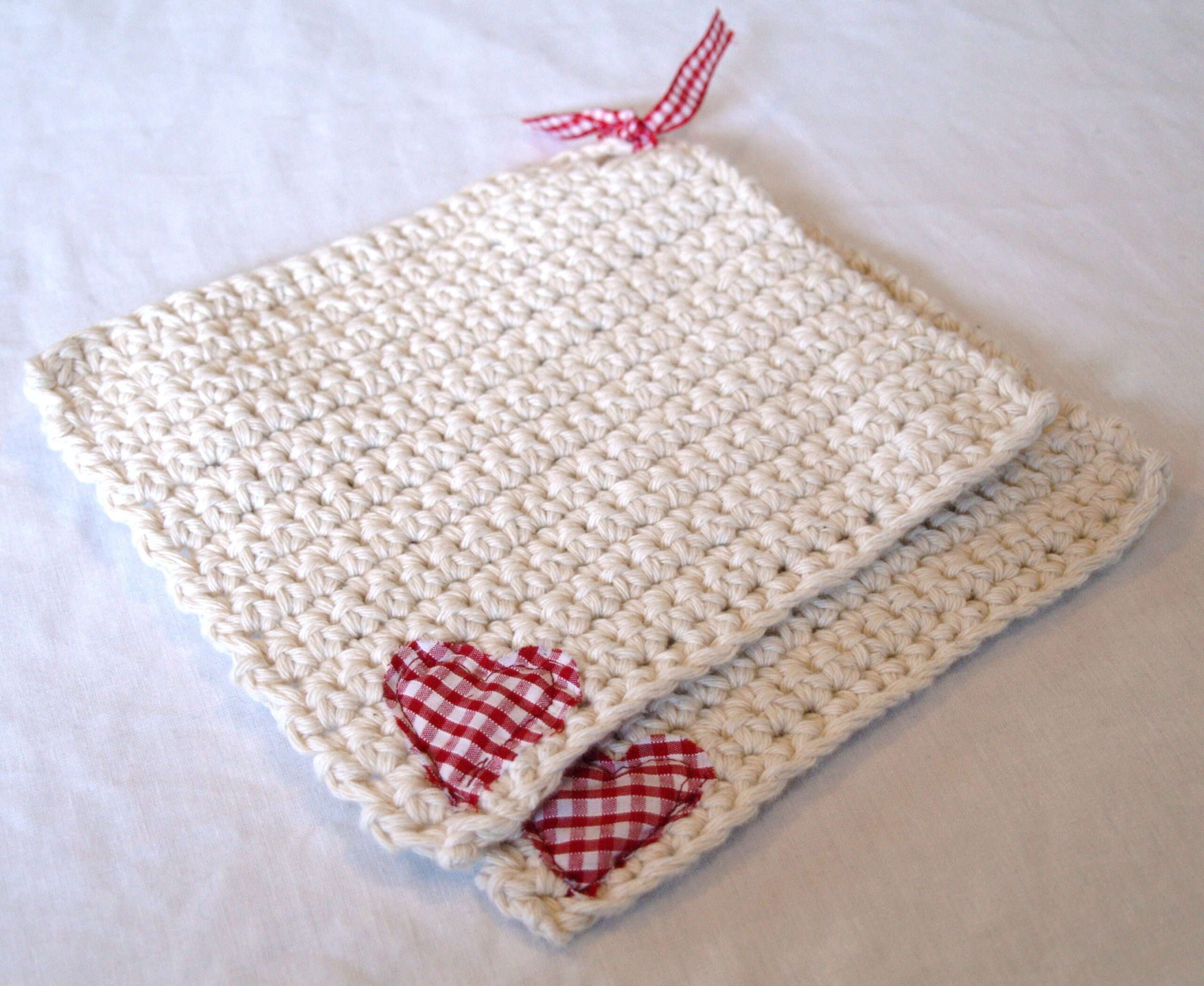 Two white handmade potholders with small red heart patches