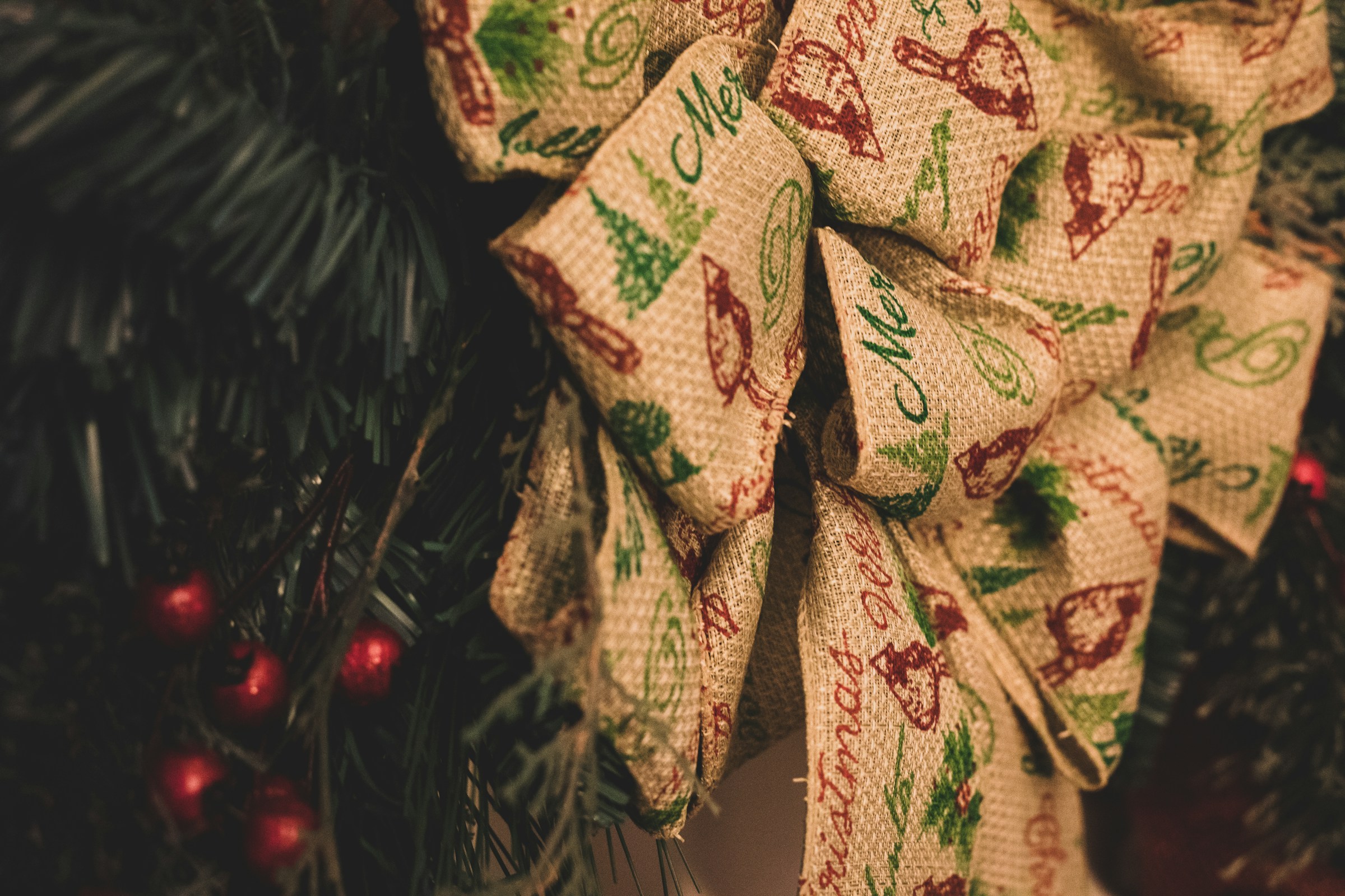 Burlap ribbon bow with a holiday print tucked into Christmas tree branches