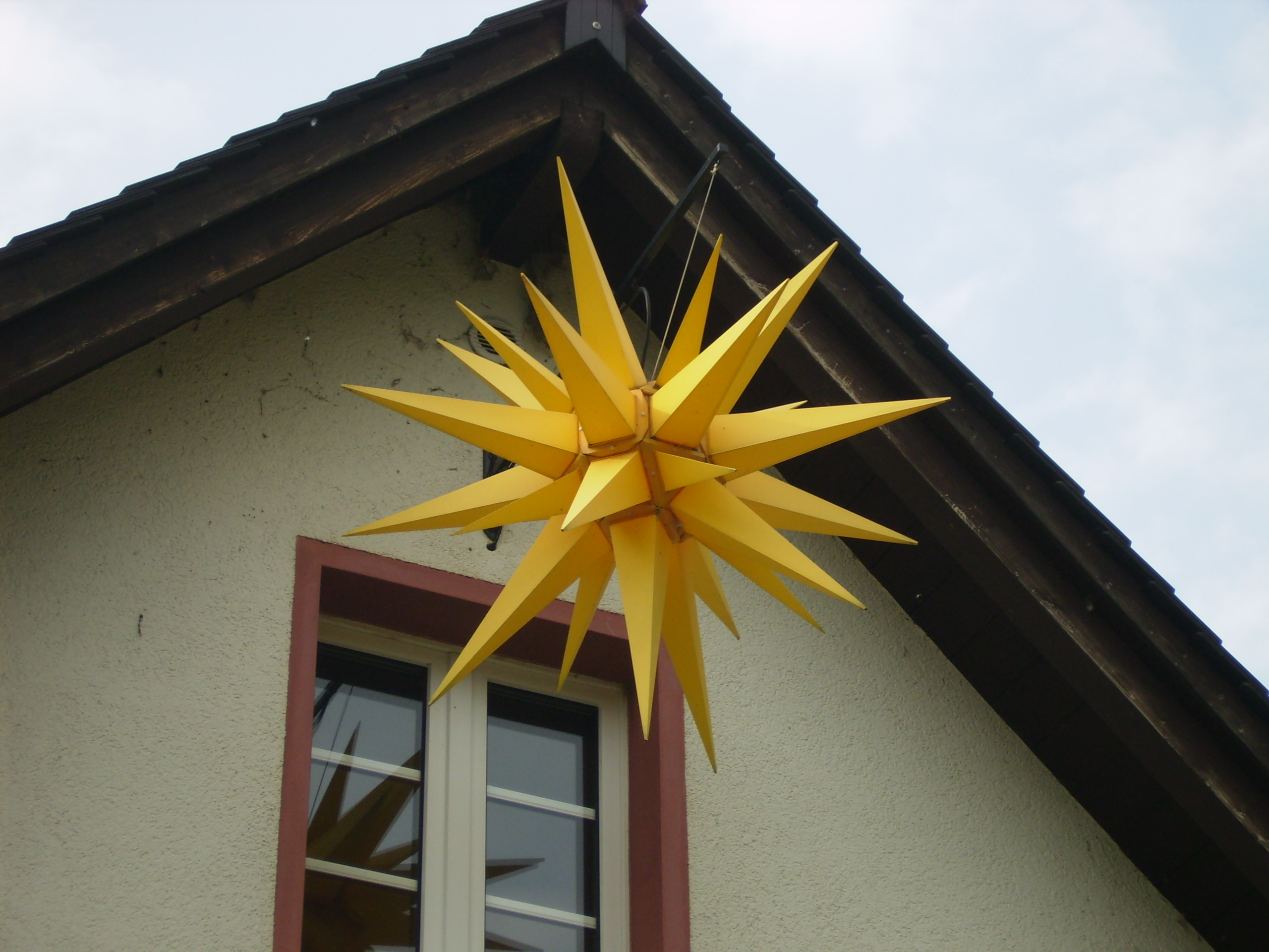 Yellow Moravian star hanging on the gable of a house