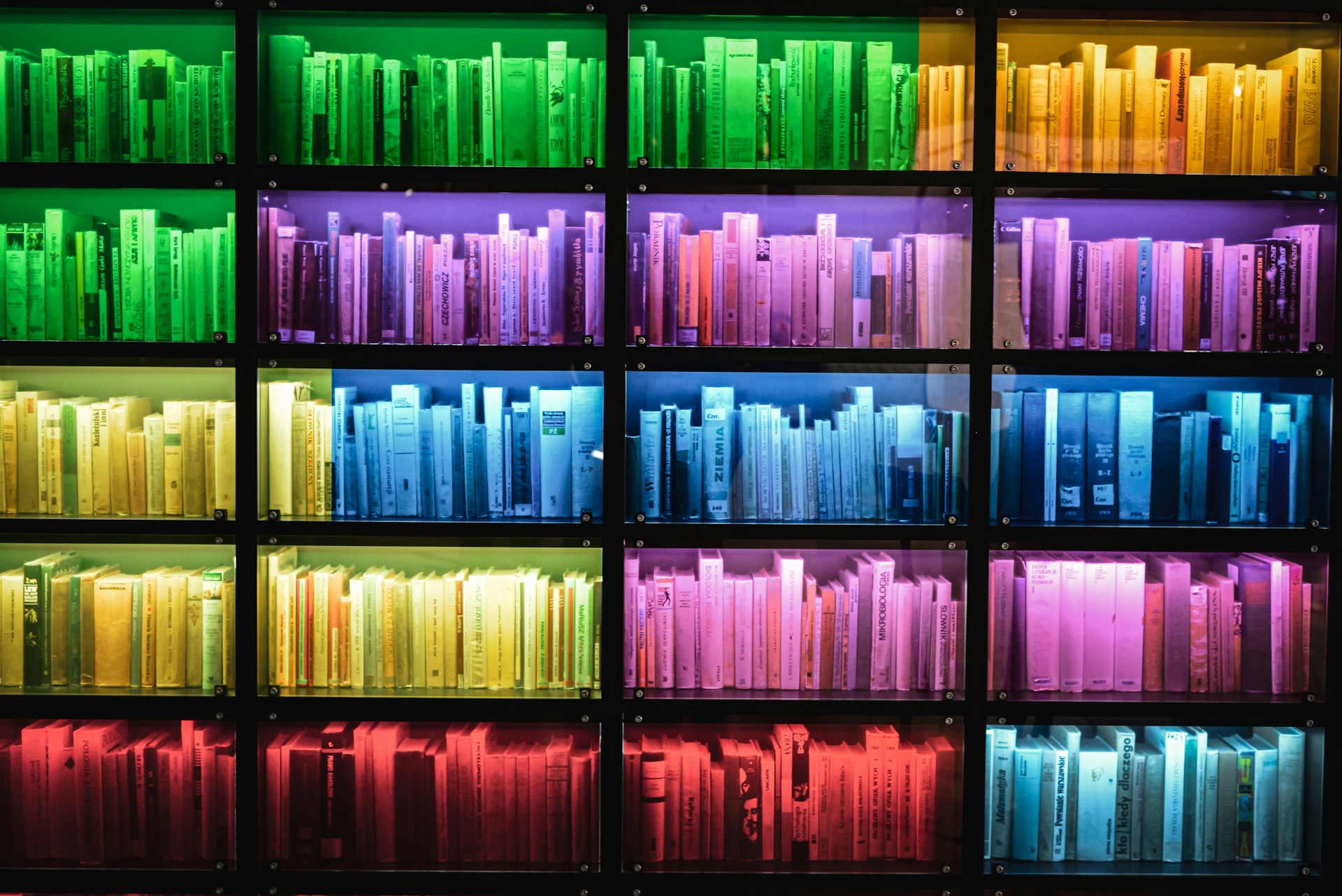 Home library ideas with shelves of books sorted by color in a rainbow