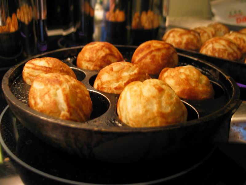 Small round pancakes cooking in a cast iron pan with round wells