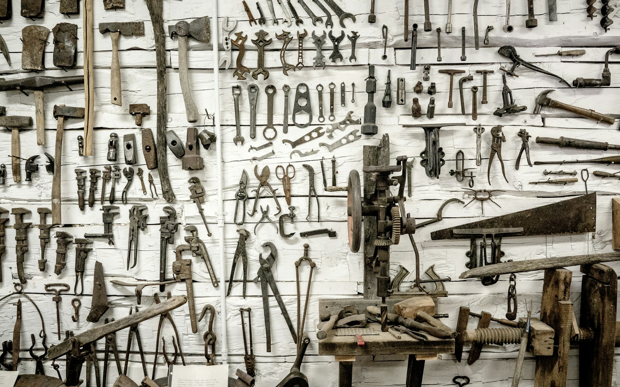 A workshop wall covered with rows of old hand tools