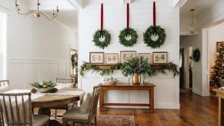 Christmas wall decor with three green wreaths hung in a row from long red velvet ribbons