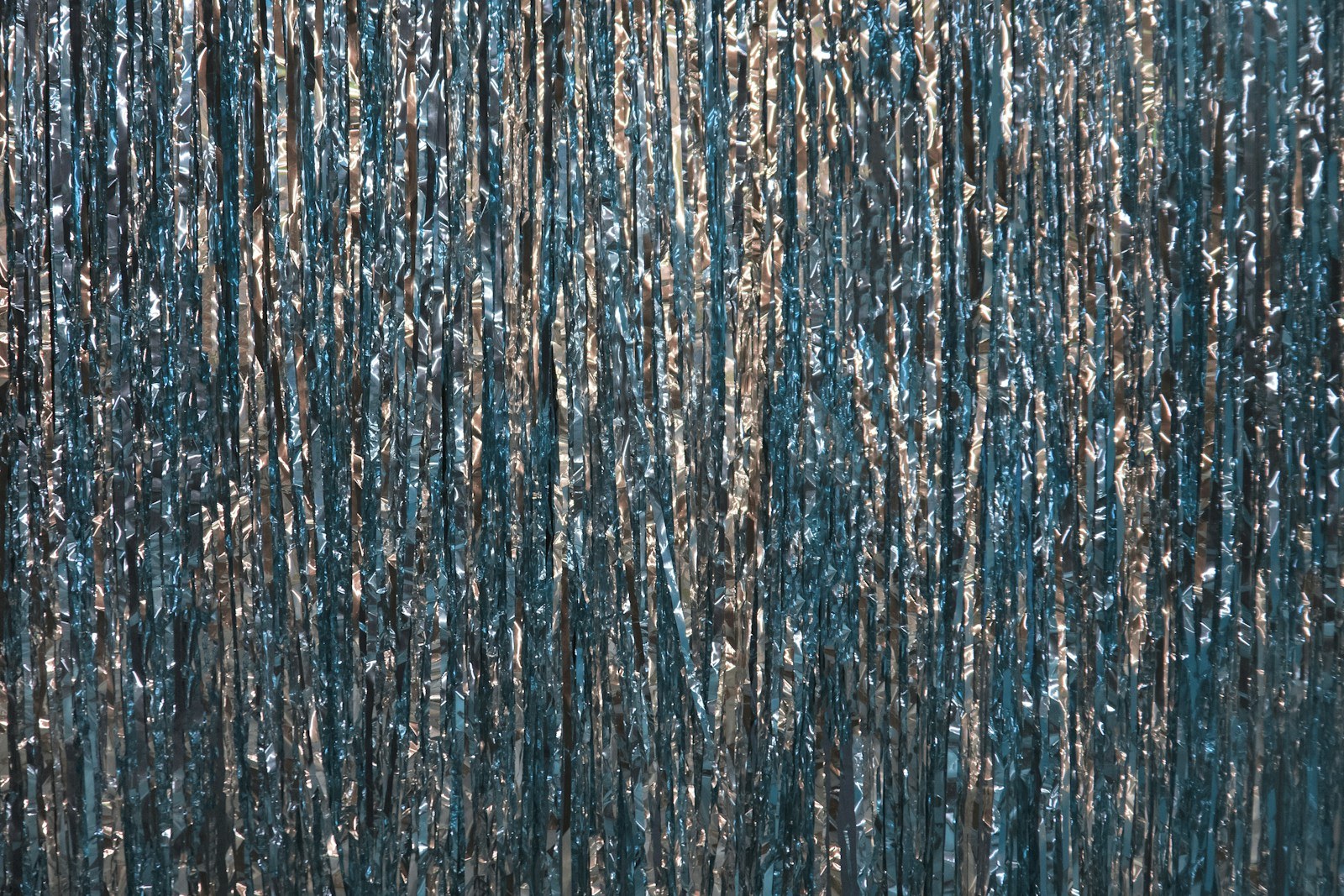 Shimmering curtain of silver foil strands against a blue background