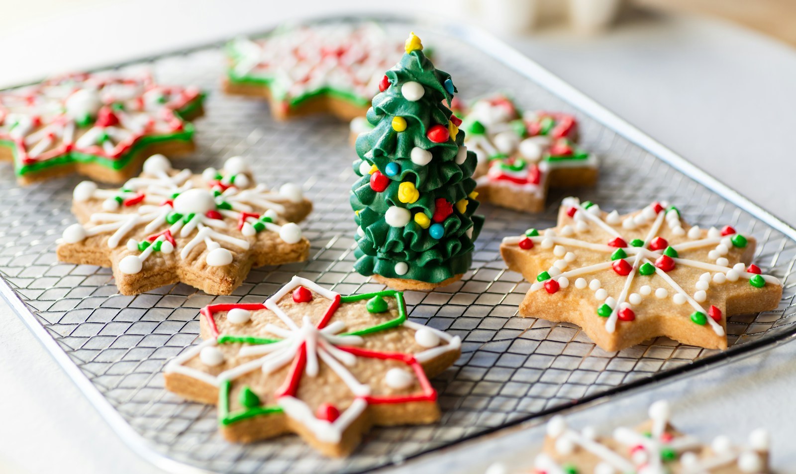 Andy Warhol Christmas cookie decorating with star and tree cookies iced in bright red, green and white on a cooling rack