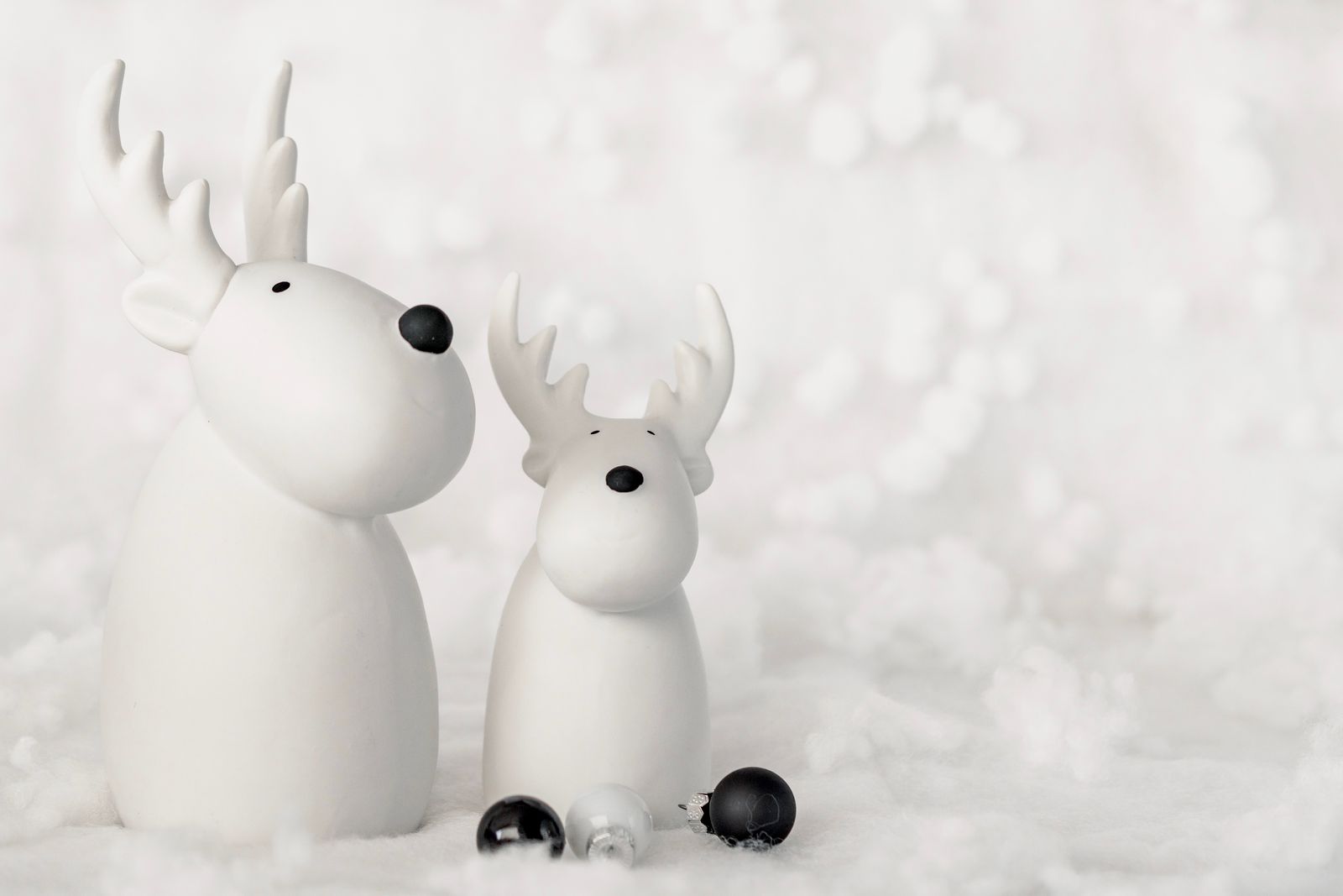 Two white ceramic reindeer figures on fluffy white faux snow