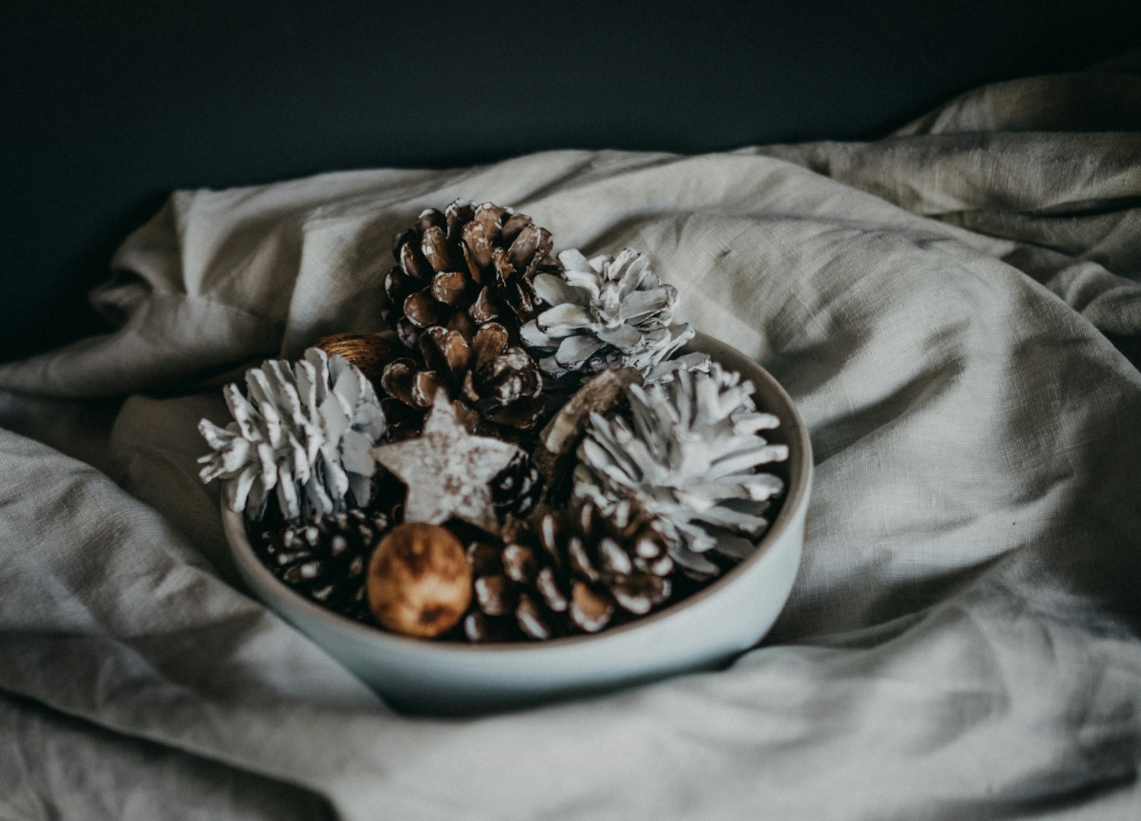 Pine cone Christmas crafts: a bowl of white-washed pine cones on soft linen